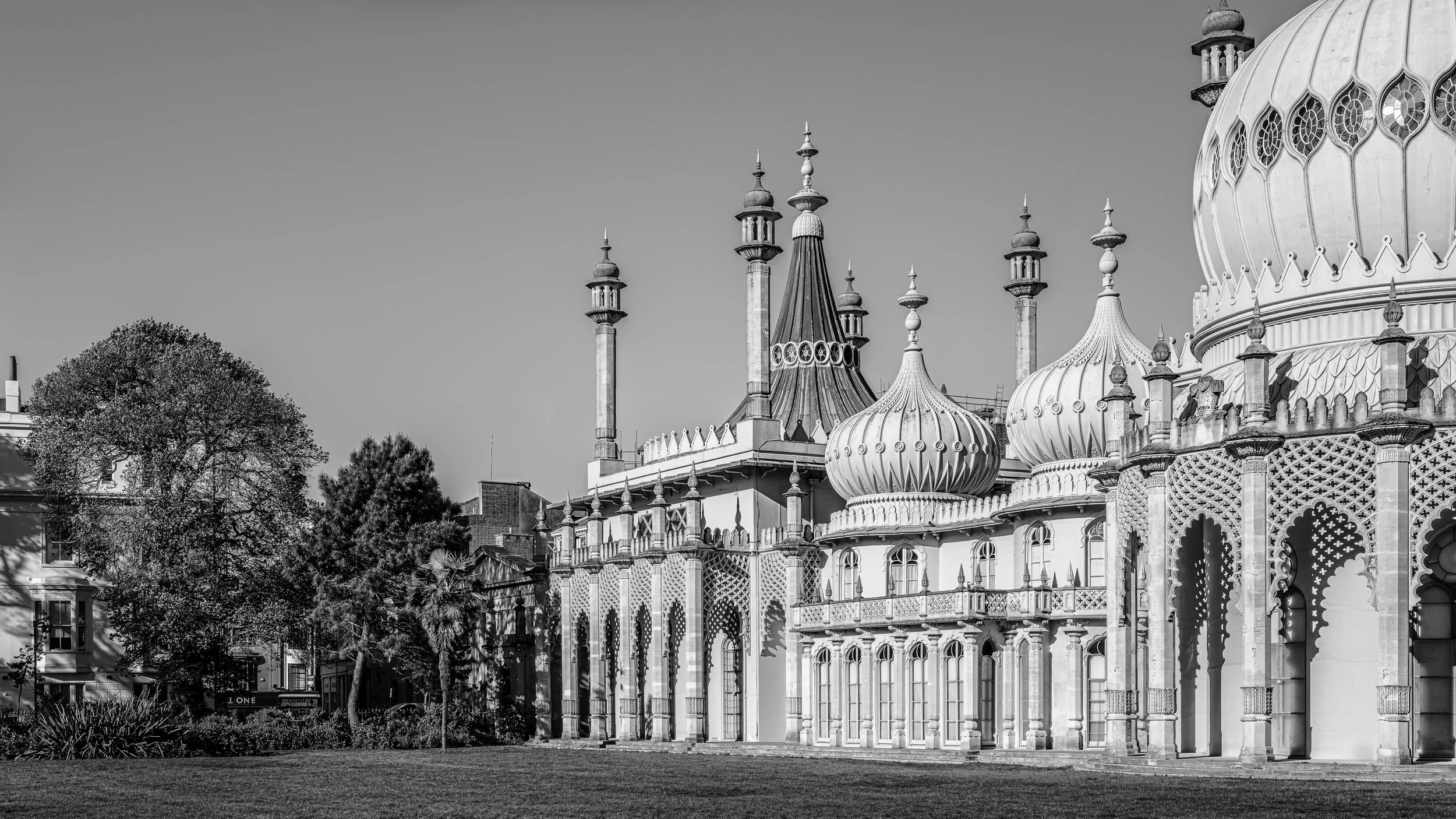 Black and white photo of ornate palace with onion domes and minarets, with trees and sky in the background.