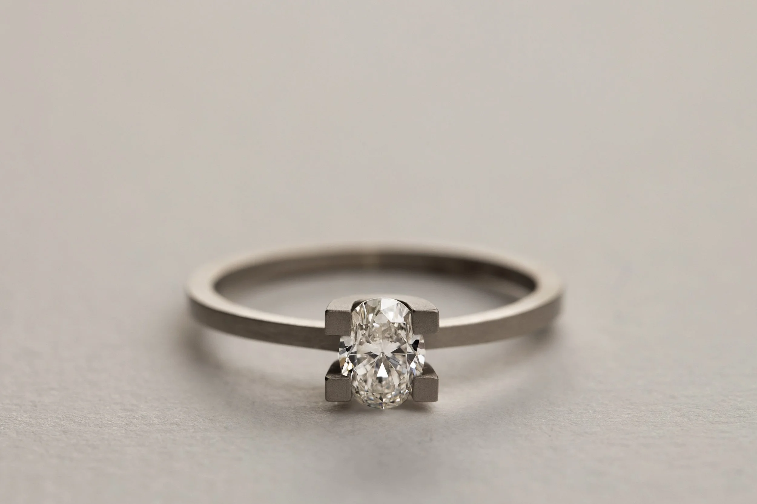 A silver engagement ring with an oval-cut diamond in a four-prong setting on a neutral background.
