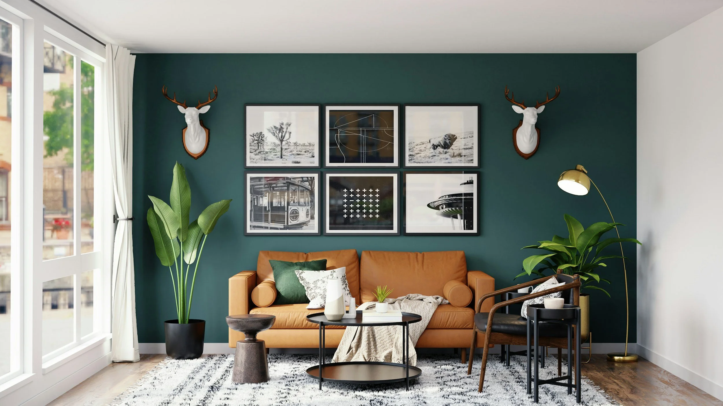 Modern living room with a green accent wall, framed black and white art, wall-mounted deer head decor, tan sofa with pillows, potted plants, black coffee table, and a standing gold floor lamp.