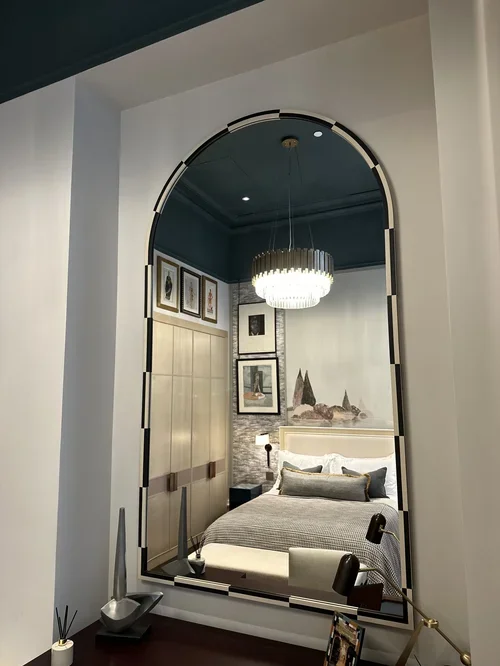 Professional mirror hanging technician from Gilbert Art Services installing a large, heavy art-deco mirror in a luxury London residence with heavy duty fixings, positioned correctly to reflect the pictures that have been hung opposite it.