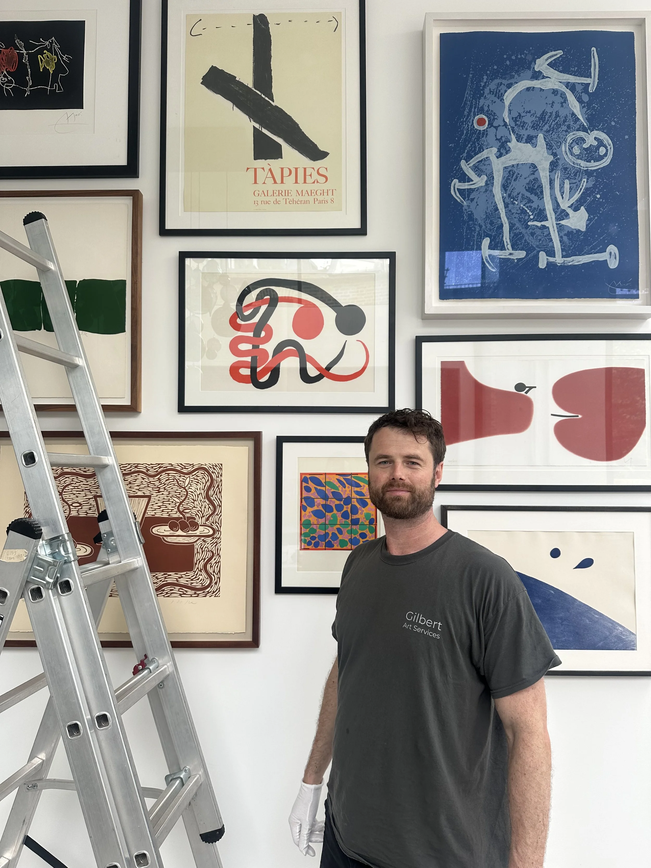 Gilbert Art Services technician professionally hanging pictures in a gallery wall format in London