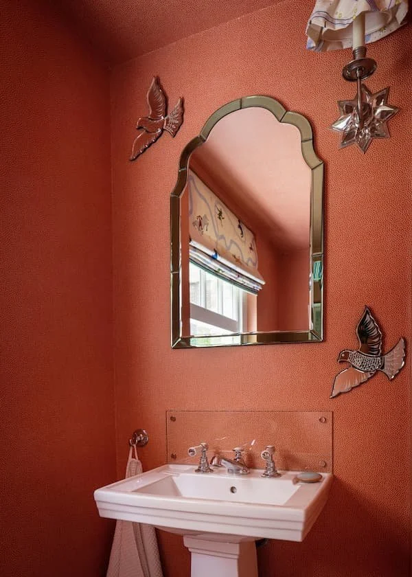 mirror hung in bathroom on red wallpaper wall