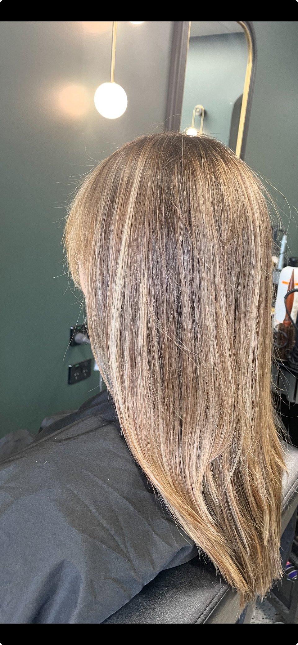 Close-up of person with straight, blonde highlighted hair in a salon setting.