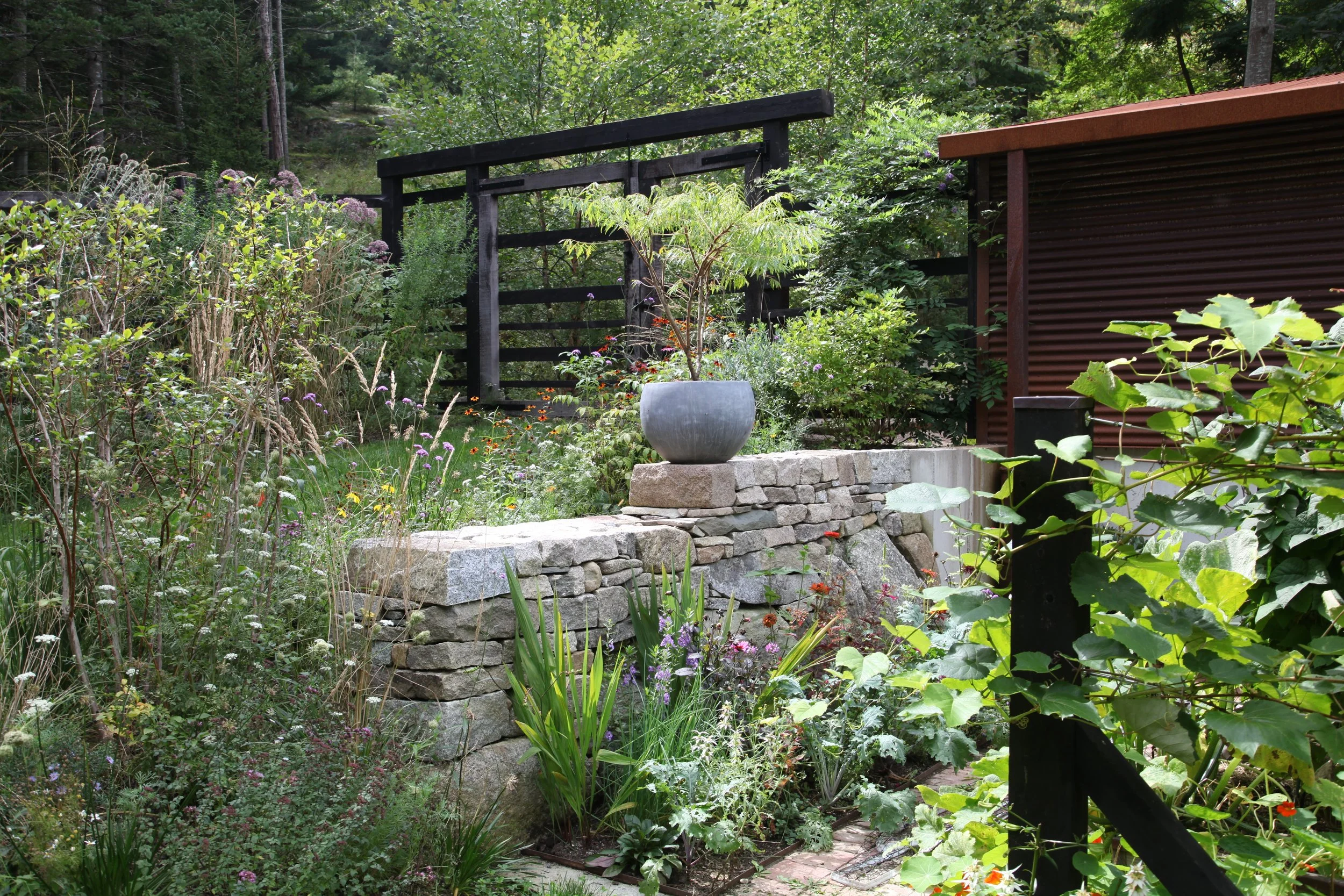 Mixed stone retaining wall carves out space for the vegetable and cut flower garden. 