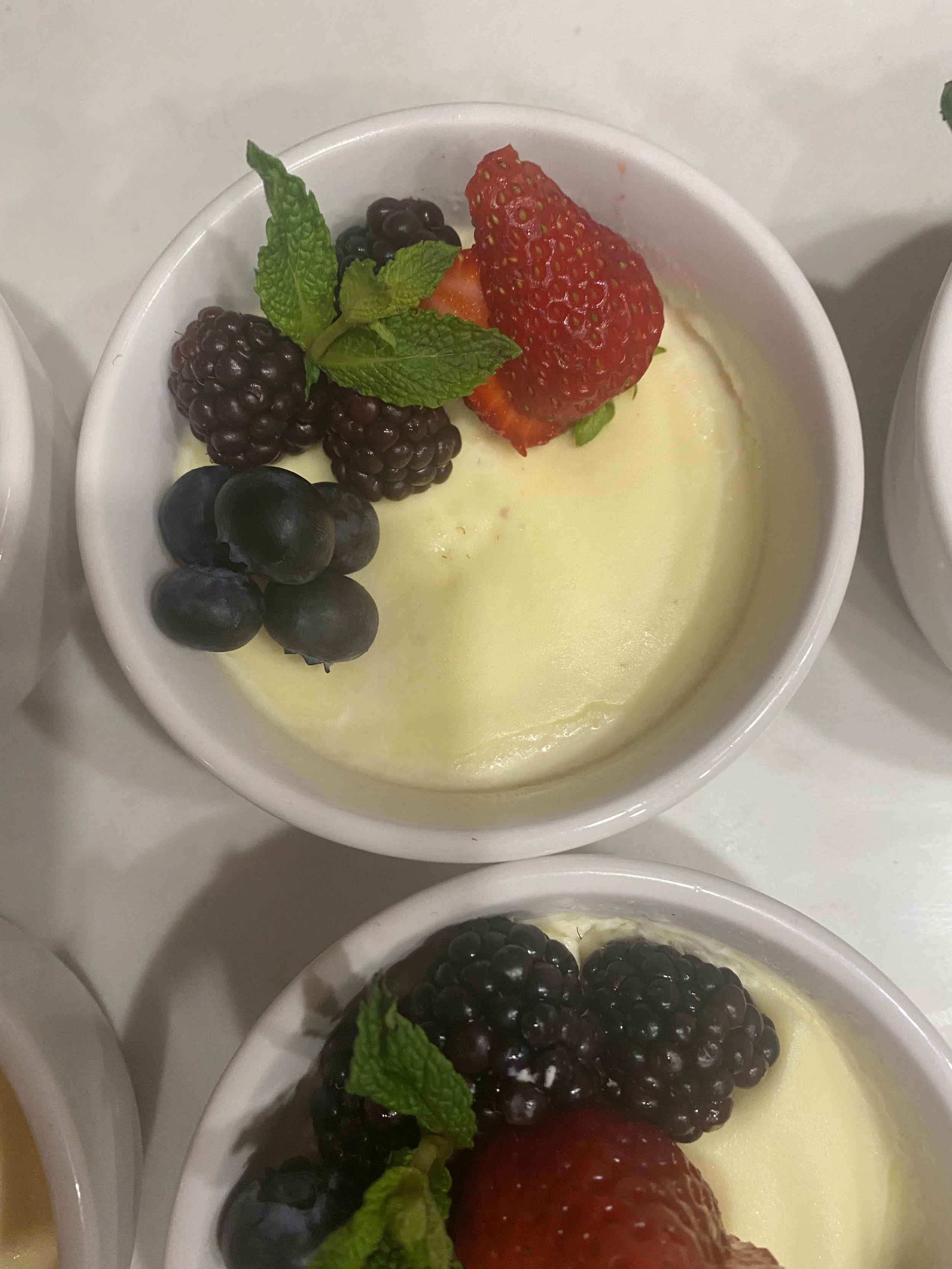 Close-up of a creamy dessert topped with fresh strawberries, blackberries, blueberries, and mint leaves at a restaurant in Phoenicia NY near Catskill Mountains