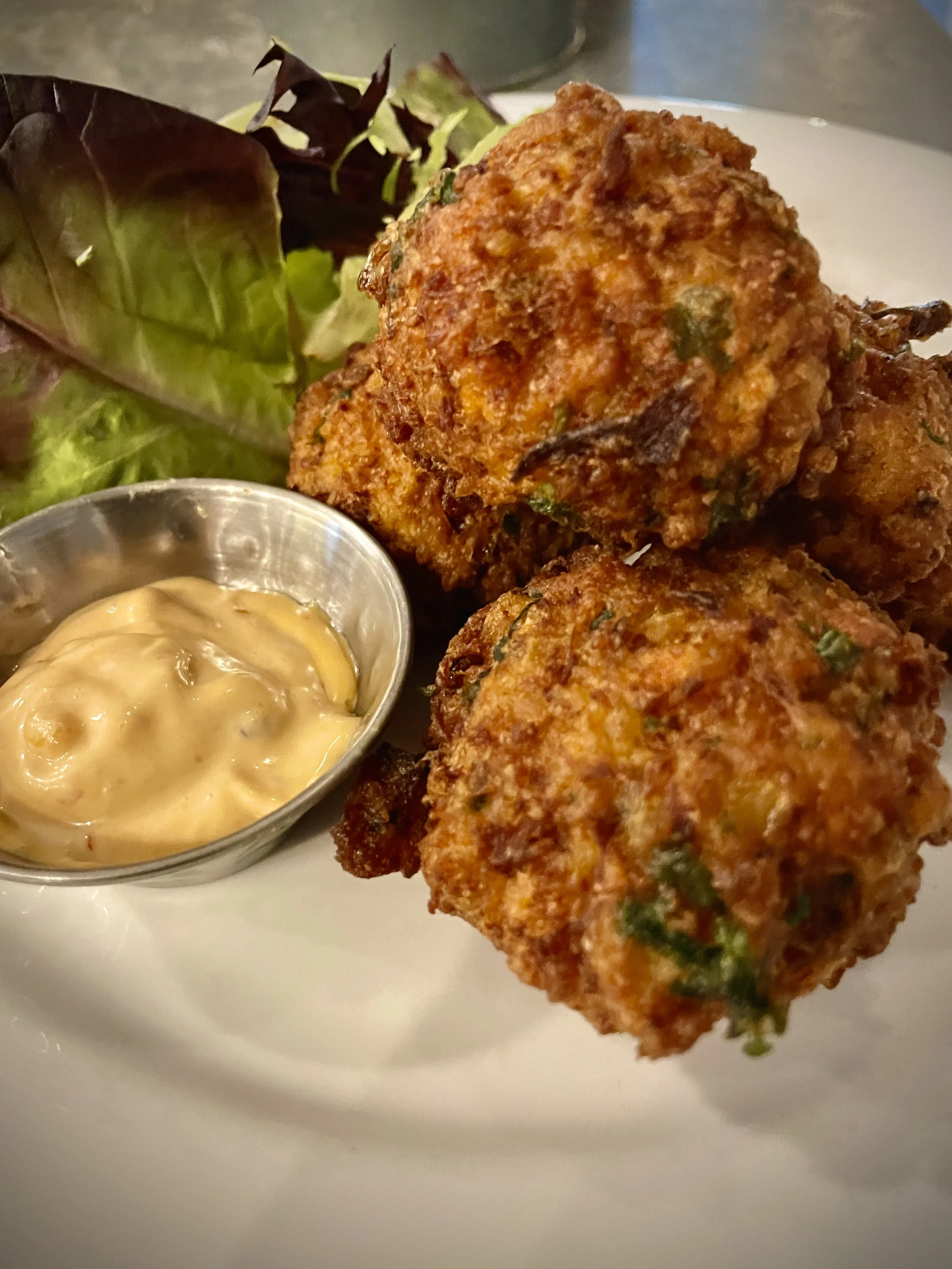 Close-up of fried crab cakes with a side of mustard sauce and a small mixed greens salad at Bettina Cafe Phoenicia NY near Catskill Mountains
