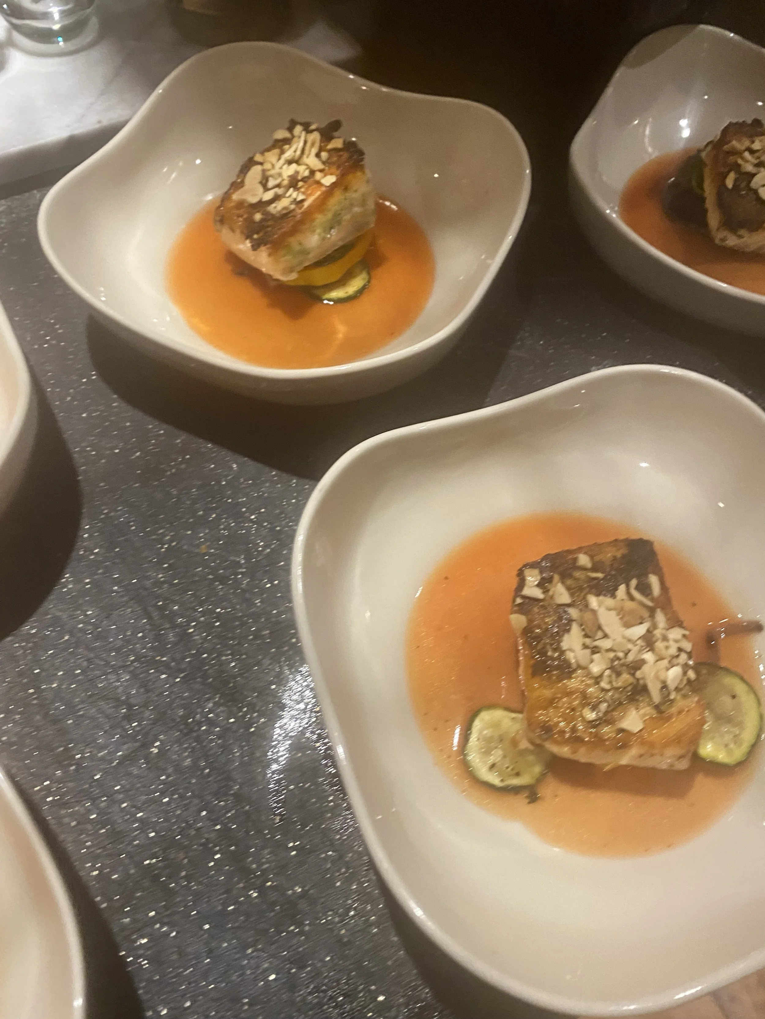 Close-up of a small, white dish containing an elegant appetizer of rolled vegetables topped with chopped nuts, served in a crimson sauce at Bettina Cafe Phoenicia NY near Catskill Mountains