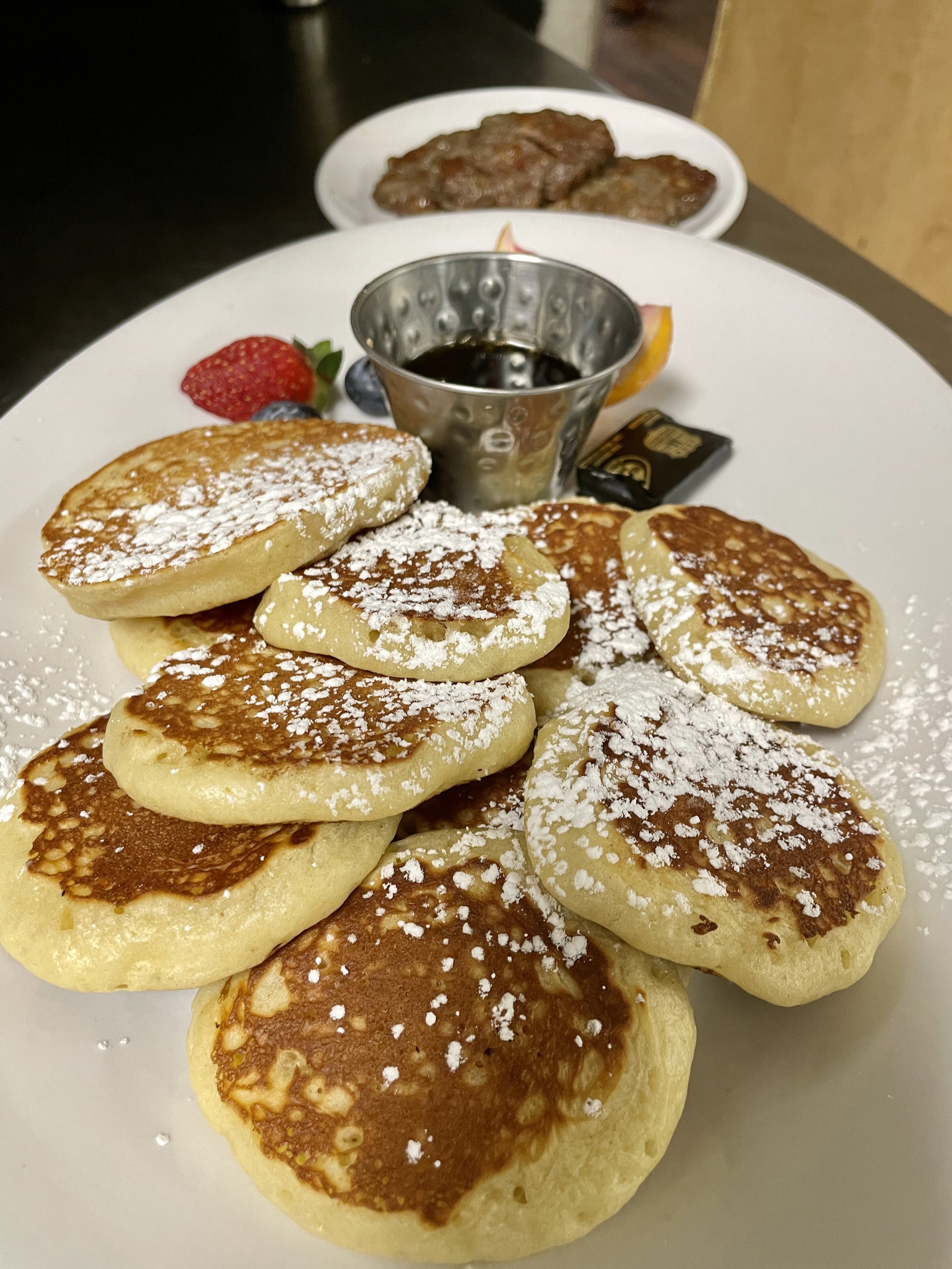 A stack of fluffy buttermilk pancakes dusted with powdered sugar and served with fresh strawberries and maple syrup..jpg