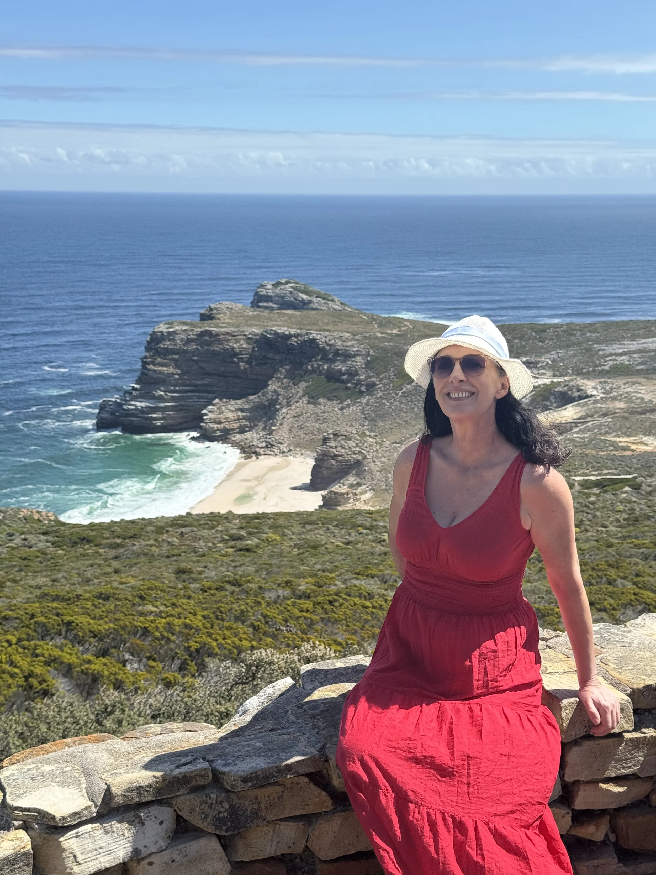Mountain range with reddish peaks and green hills in foreground under a clear sky.