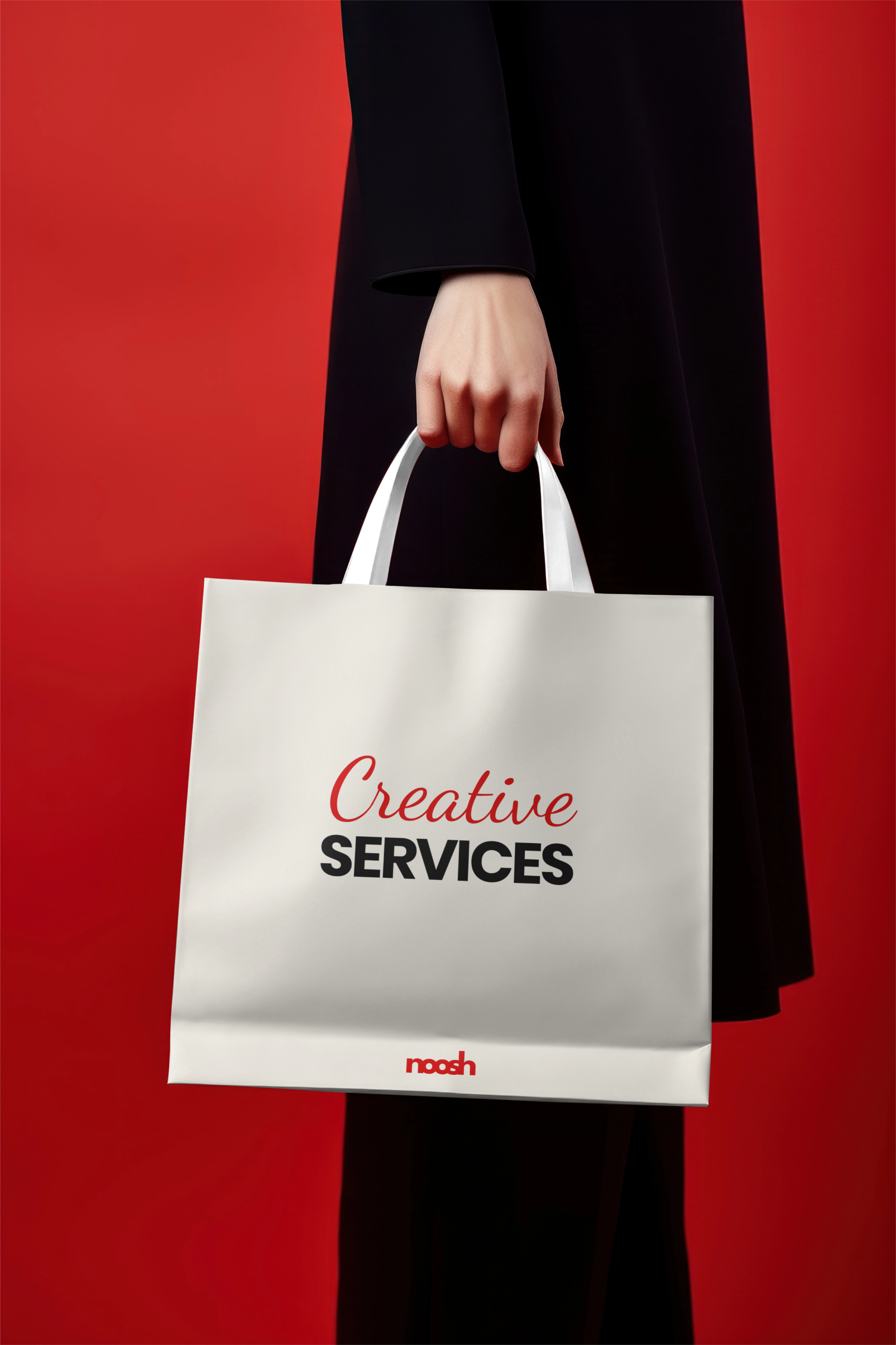 Hand holding a white shopping bag with 'Creative Services' text on a red background.
