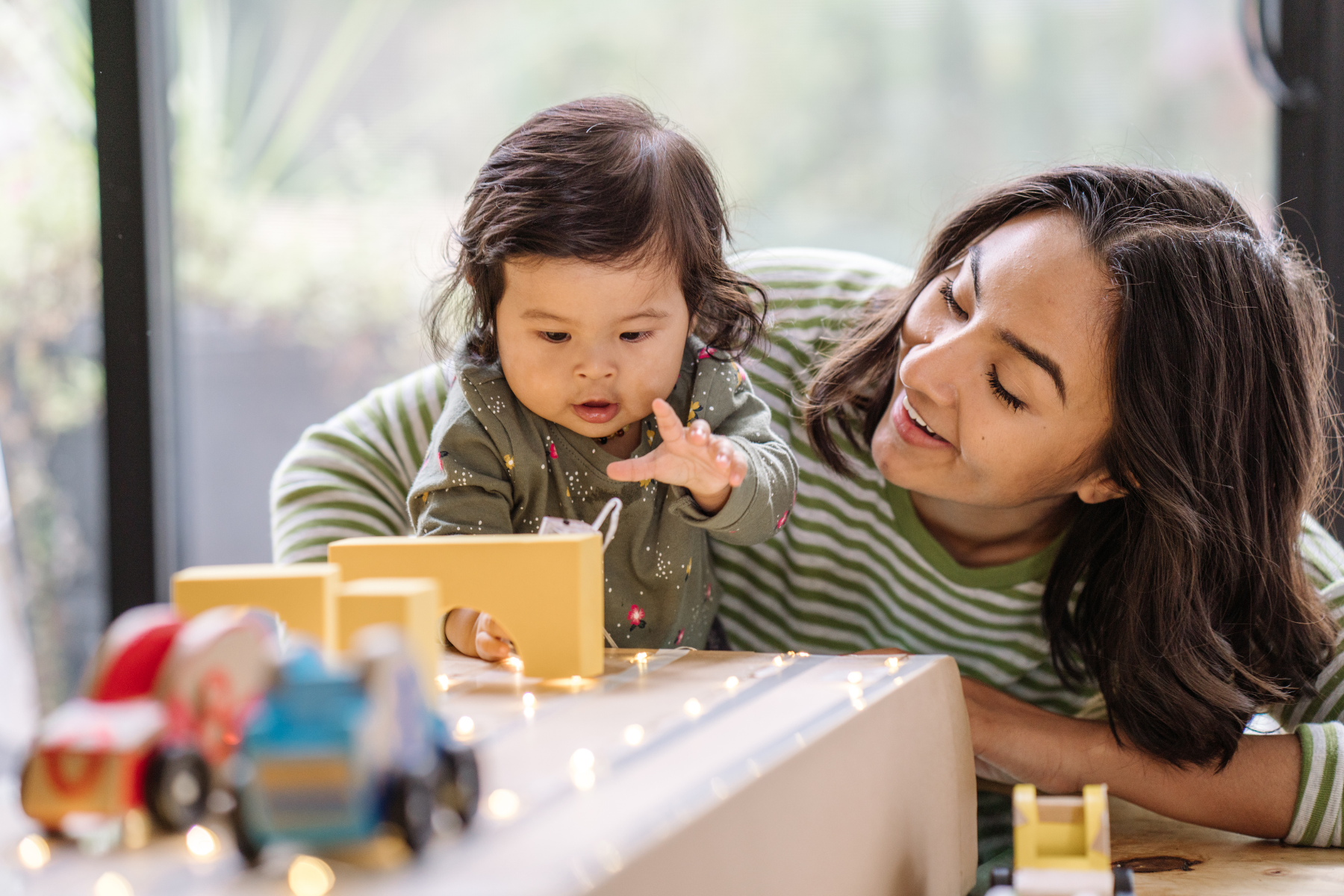 A toddler and parent engaging in motivating play with a preferred toy to encourage first words and communication during a speech therapy session.