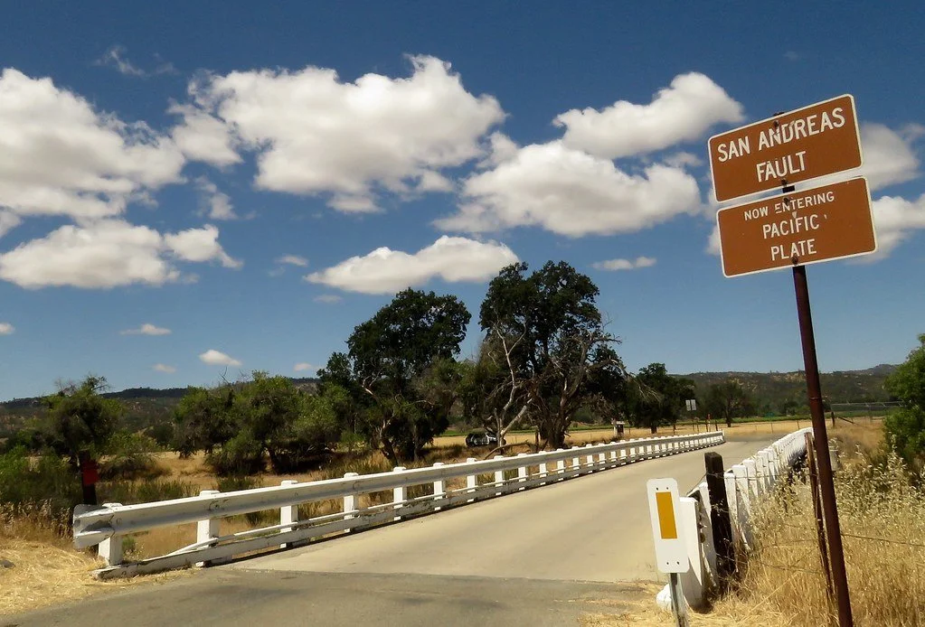 A bridge crossing the San Andreas Fault on Parkfield Coalinga Road with brown highway signs indicating the San Andreas Fault and the Pacific Plate.