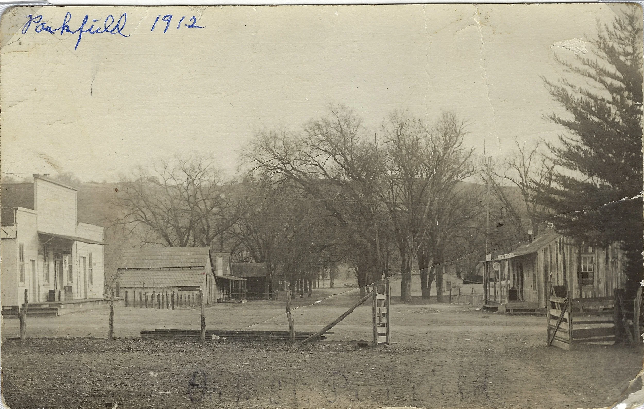 Historic black-and-white photograph of Oak Street in Parkfield, 1912 showing a rural scene with several trees, a few small buildings, and a dirt road with fences.