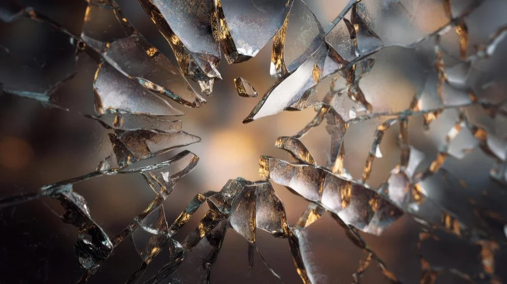 Close-up of broken glass with sharp edges and reflections.