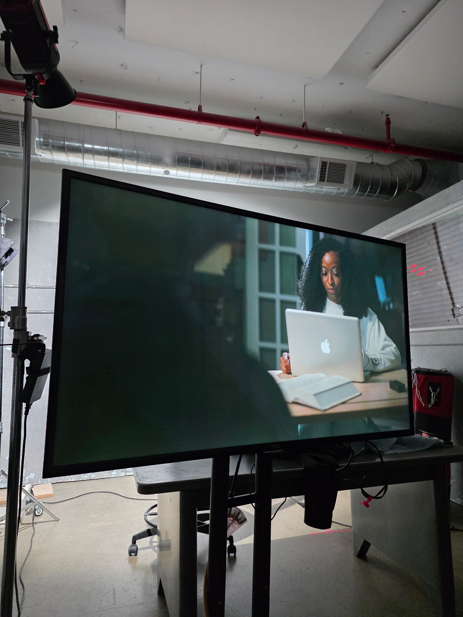 Video production setup with on-set monitor and talent using a laptop.