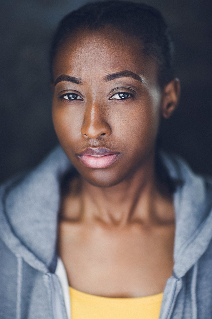 Portrait of a person wearing a gray hoodie and a yellow shirt, looking directly at the camera with a neutral expression.