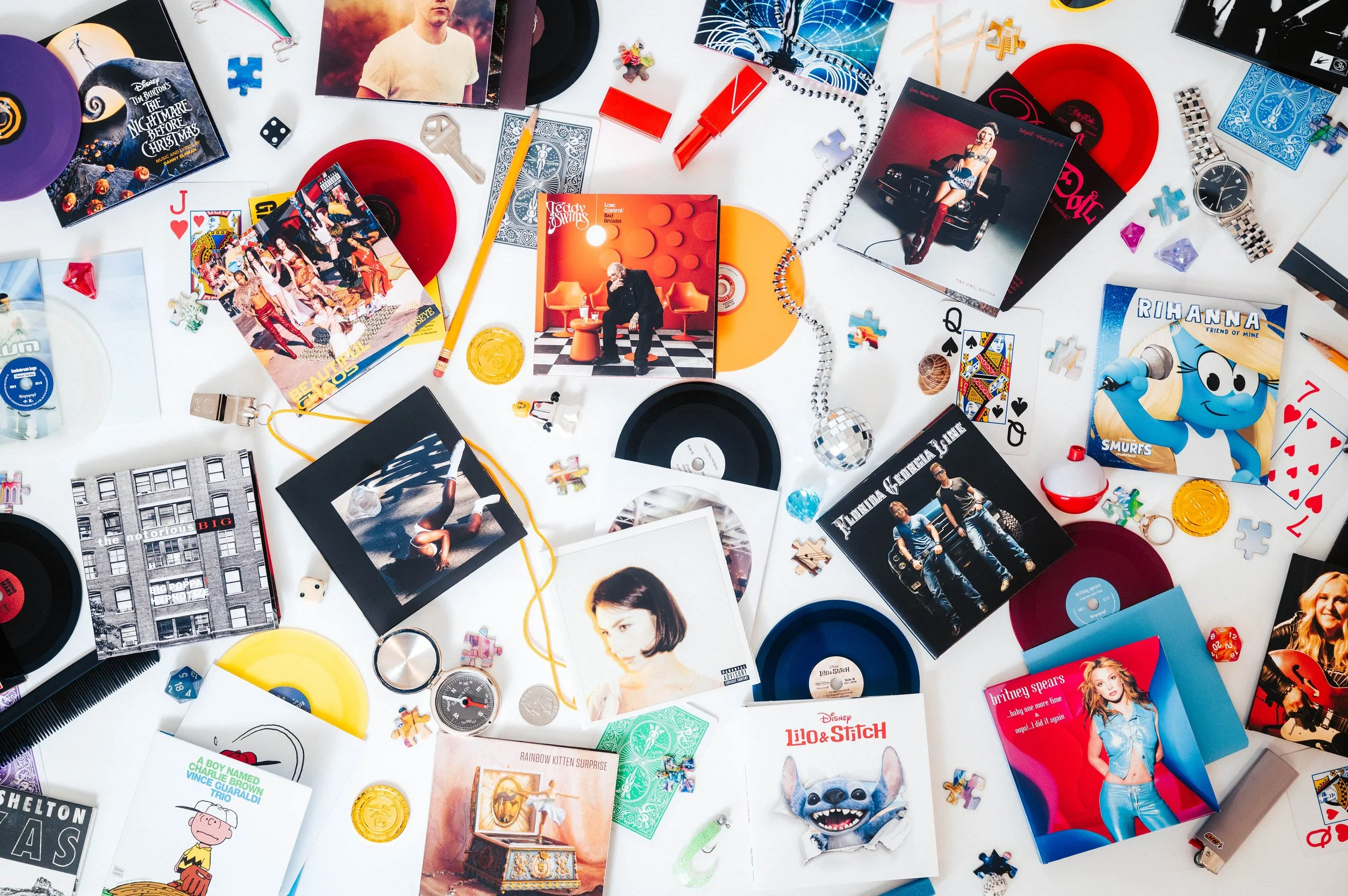 a variety of tiny vinyl records with a bunch of other small objects near them for size comparison