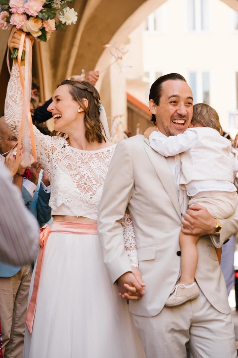 Wedding couple in Munich during their wedding is laughing, bride is holding her bouquet flowers