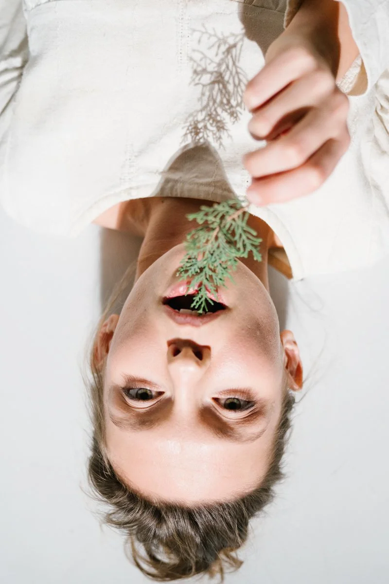 Model is laying on the floor in photo studio in Munich holding natural flowers close to her lips