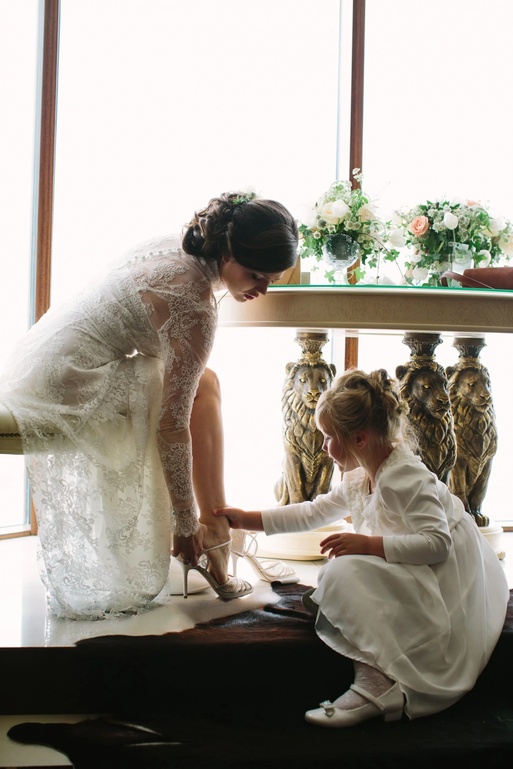 Flower-girl is helping bride to get ready with her shoes during wedding morning on Lake Como