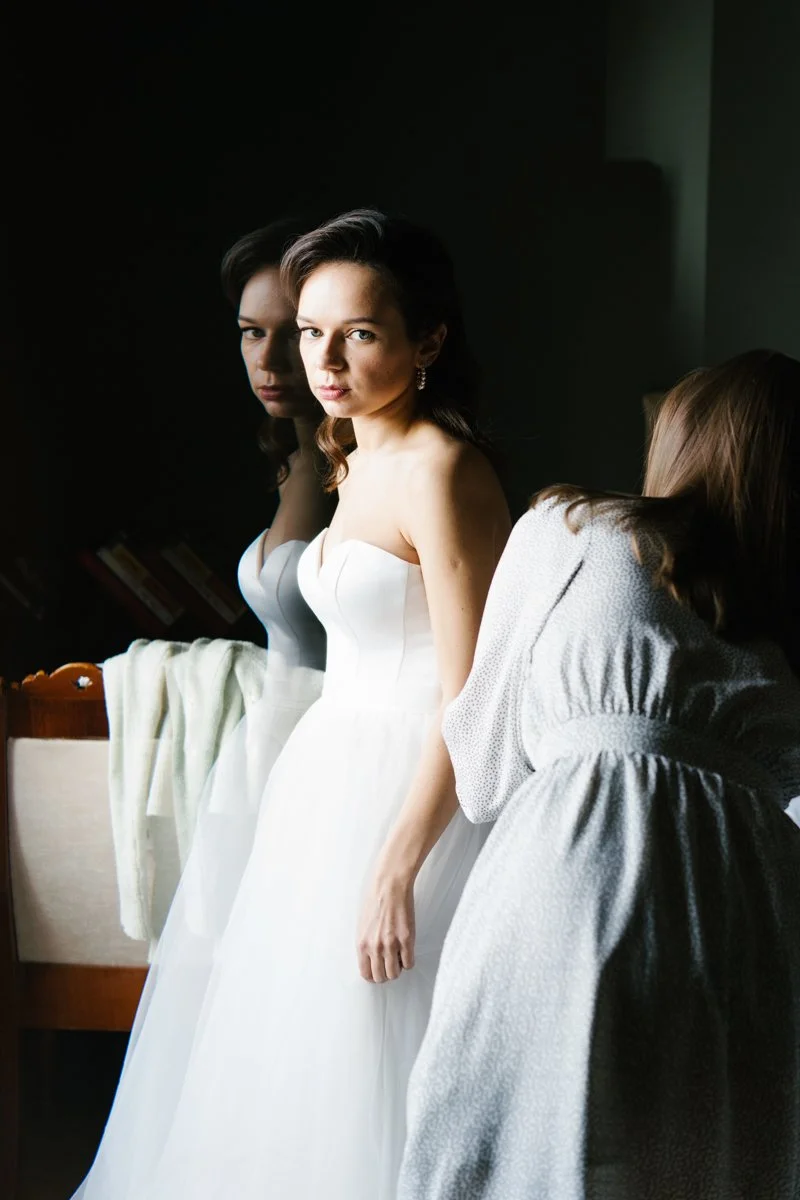 Bridesmaid is helping bride to get ready for her civil wedding