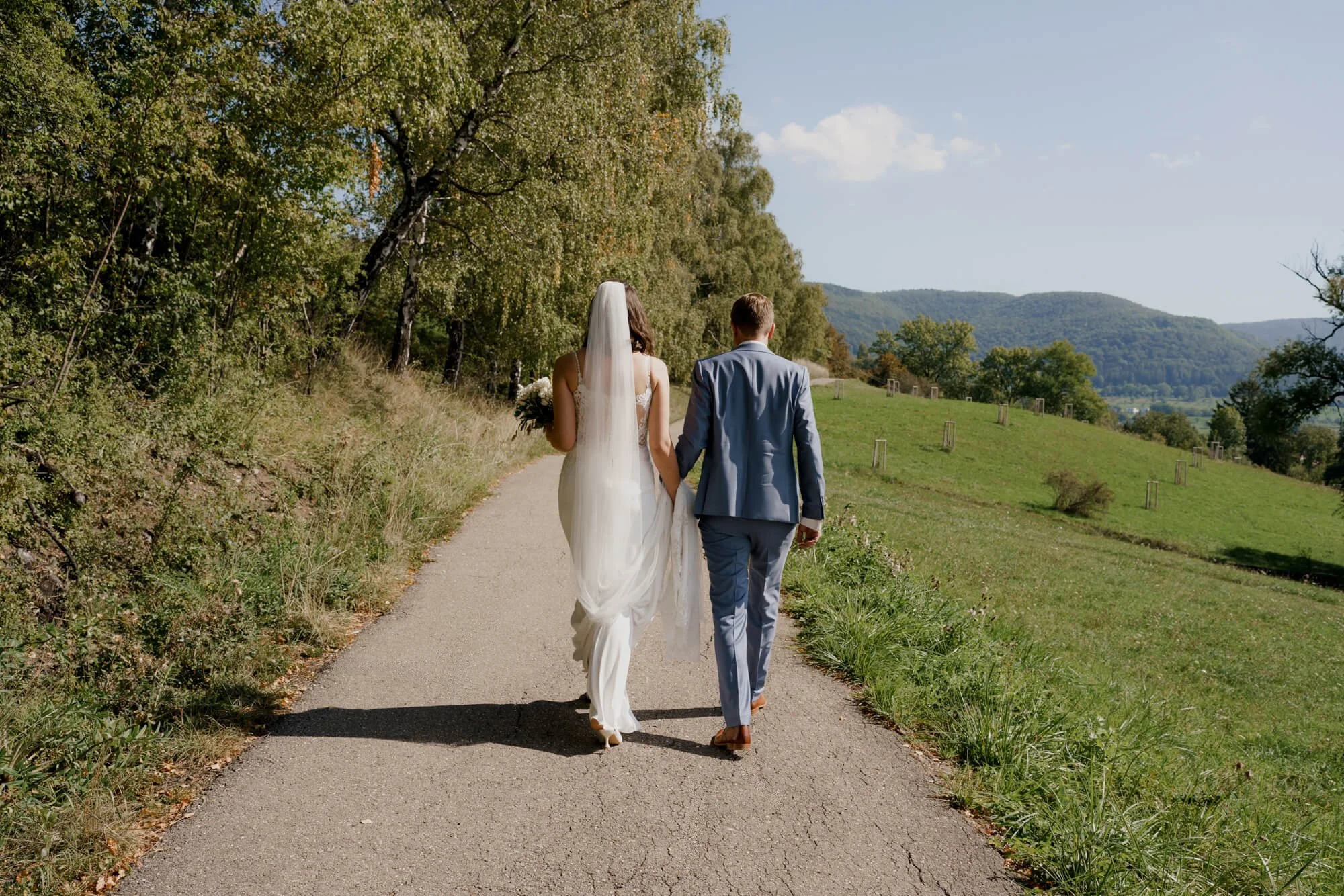 View from the back how couple is going on the road during wedding photosession in Reutlingen