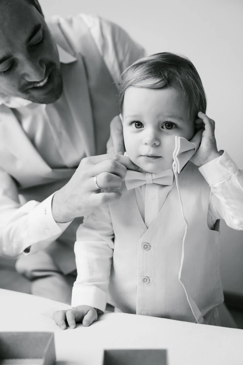 Wedding morning in Munich. Father is putting bowtie to his small child