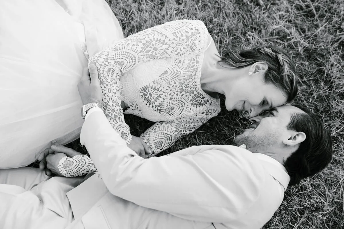 wedding couple laying on the grass, heads together posing for wedding photographer in Munich