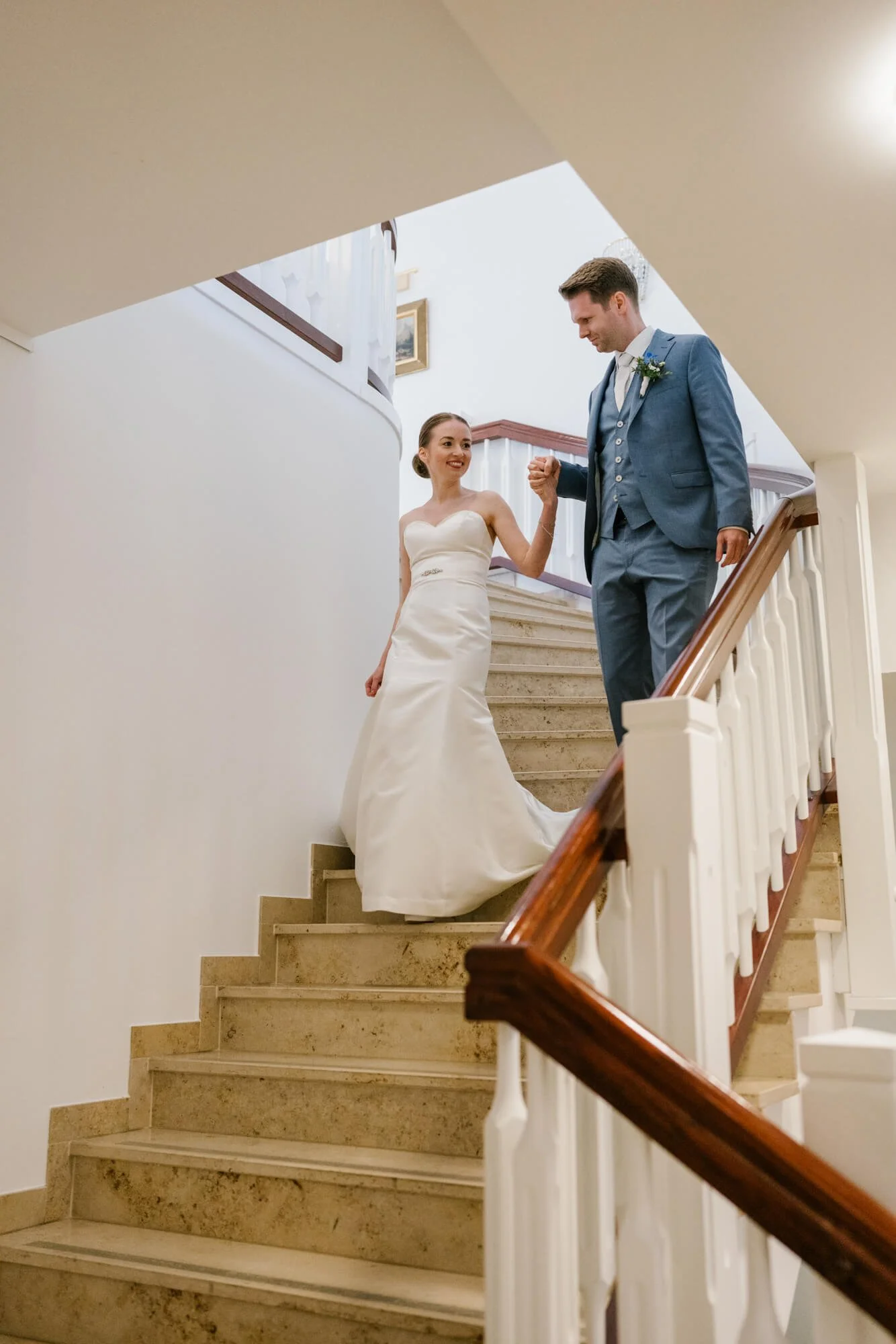 couple is going down from the stairs in wedding outfits