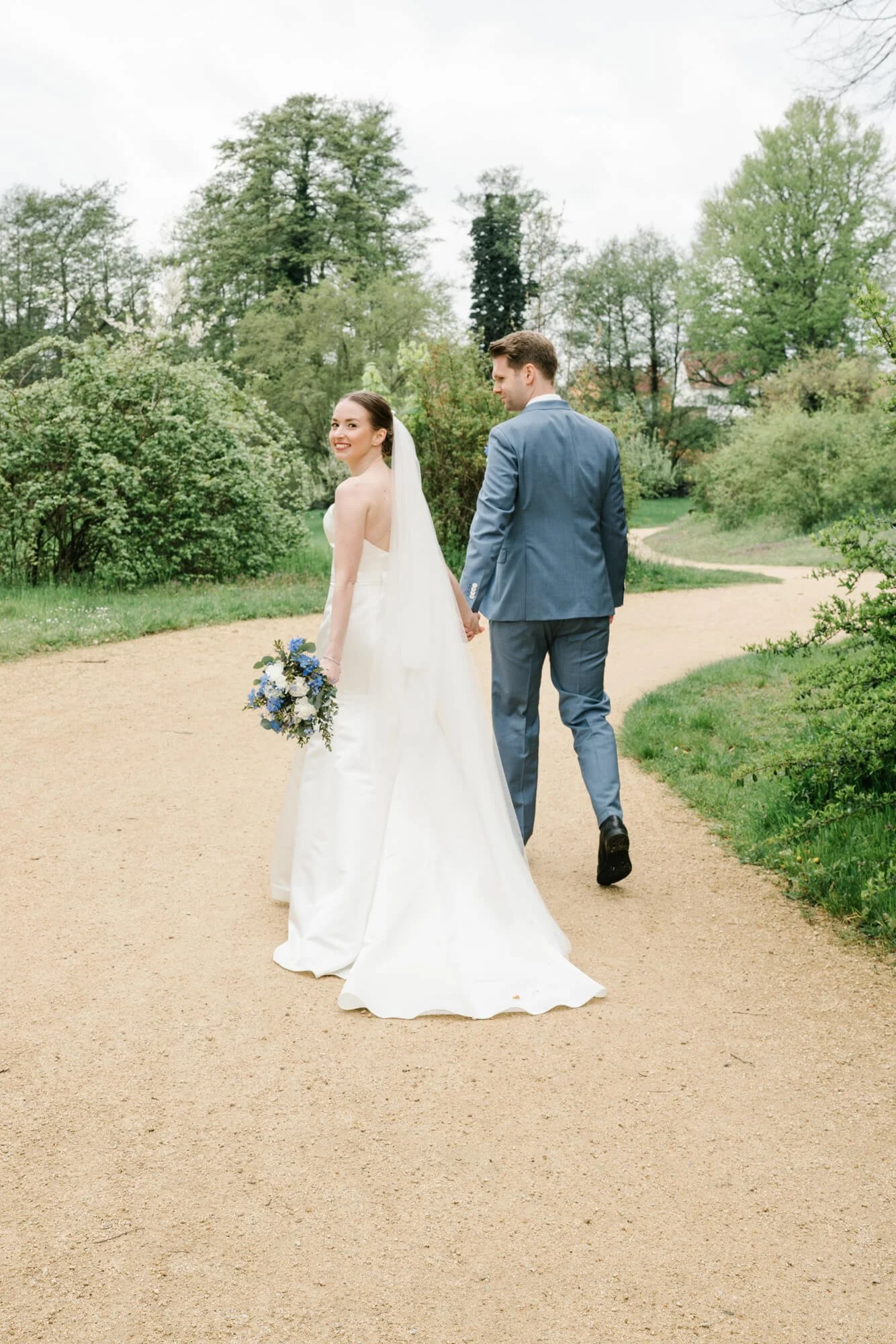 wedding couple in park Caputh, bride is looking back to wedding photographer