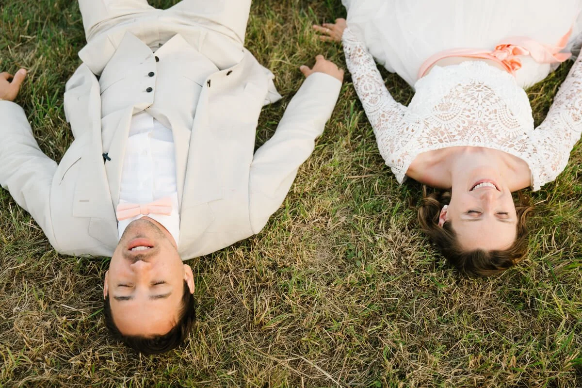 wedding couple laying on the grass posing for wedding photographer in Munich