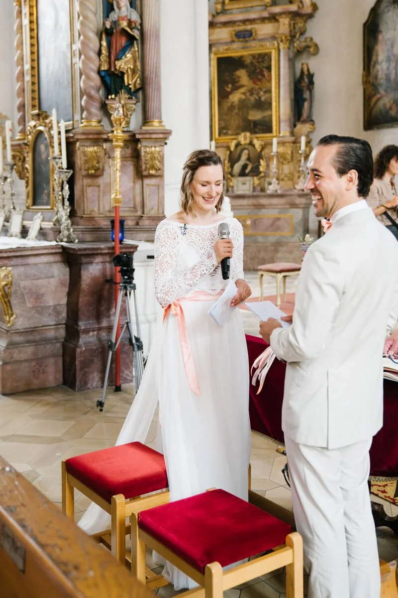 The bride is telling her speech during a church ceremony in Munich, groom is laughing