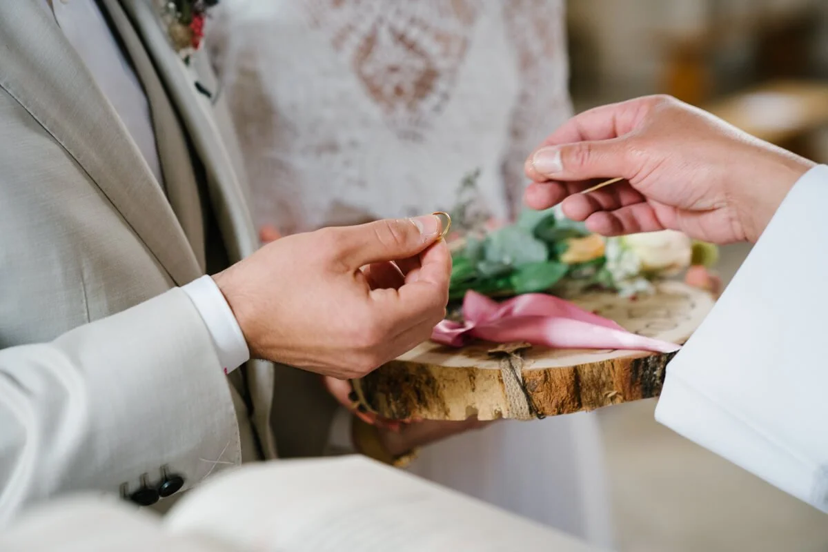 Wedding photographer Munich. Couple is enhancing rings during church ceremony