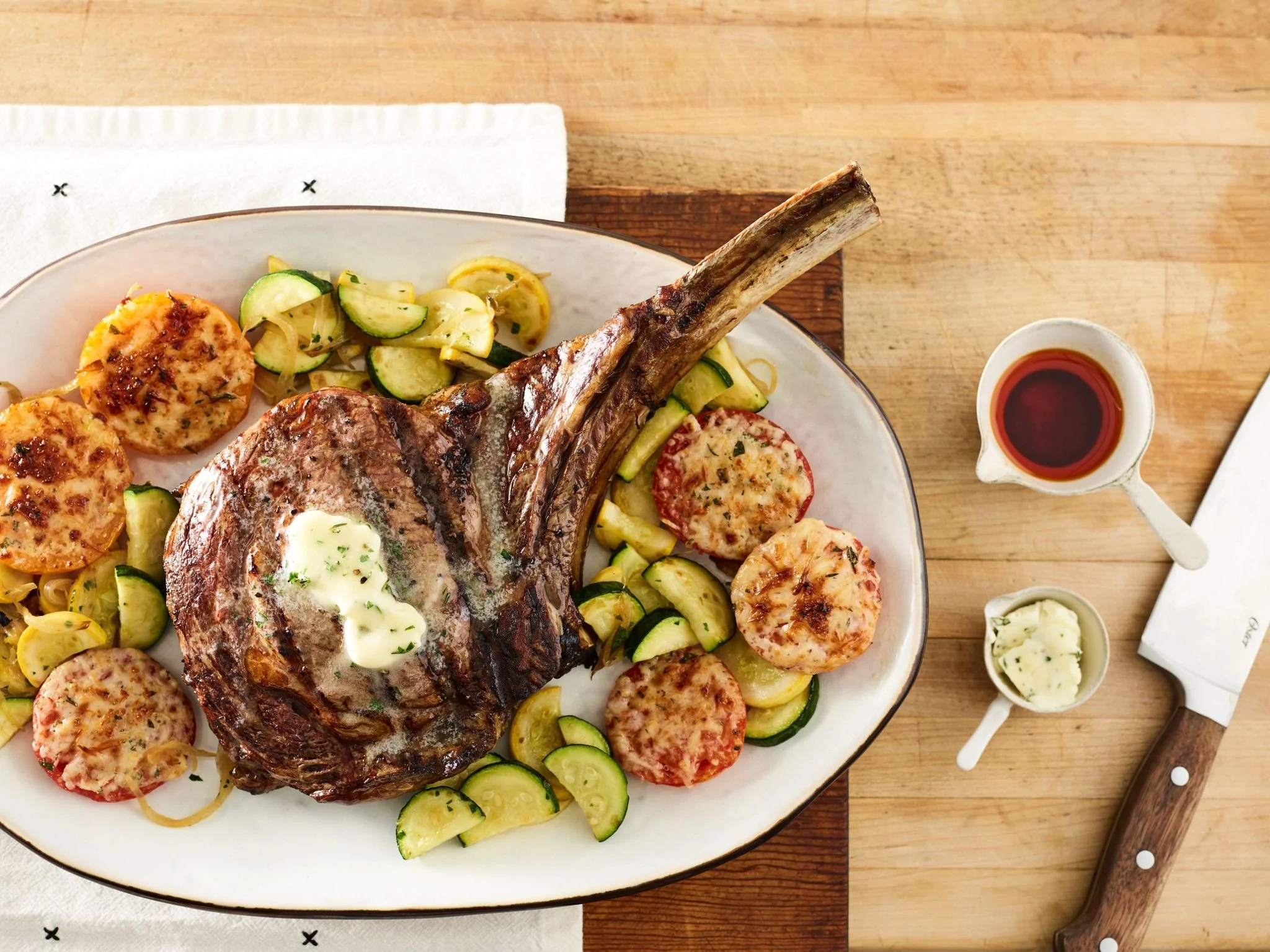grilled-cowboy-steak-with-parmesan-tomatoes-and-cucuzza-squash-compound-butter.jfif
