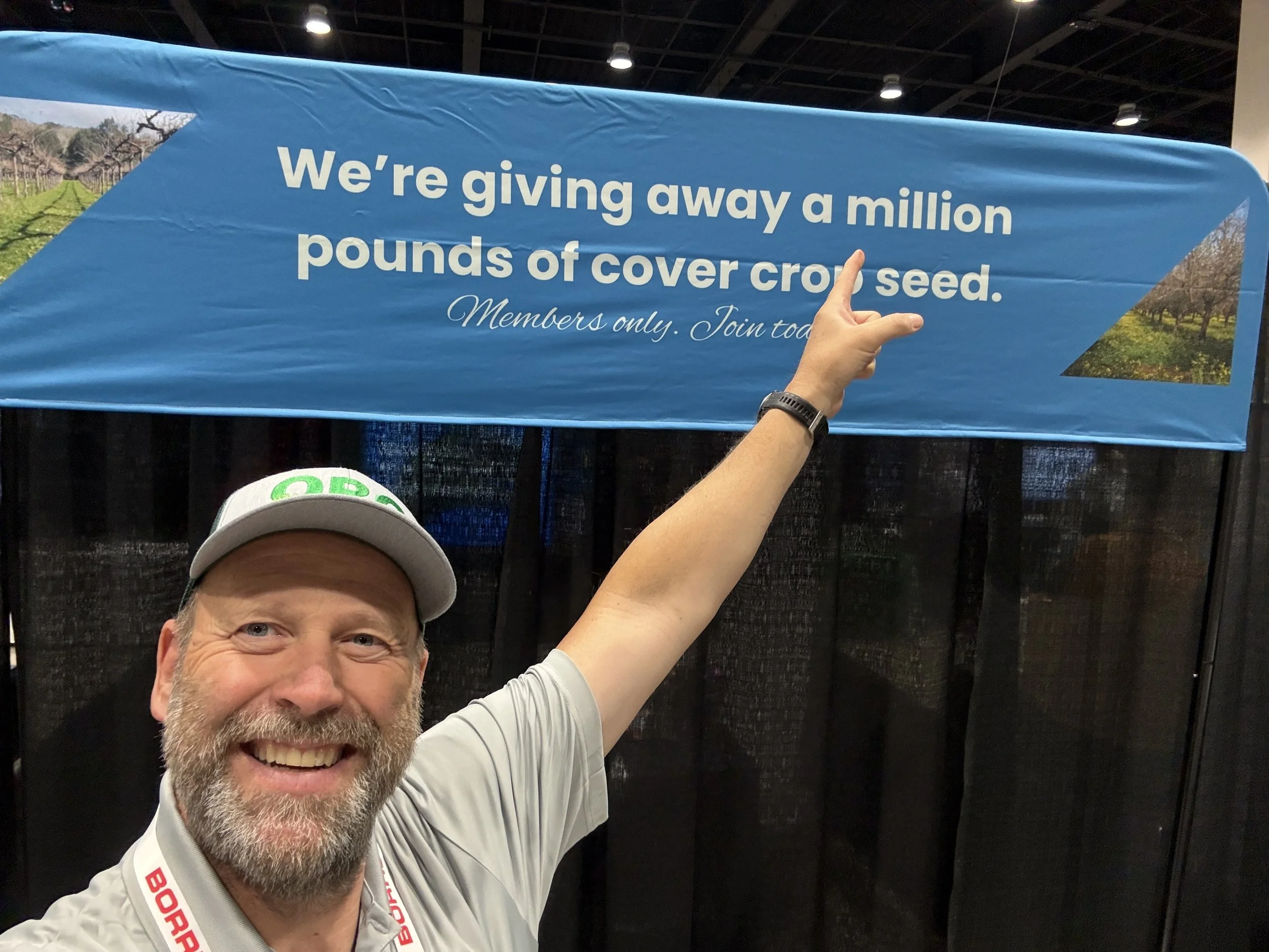 Michael Costello, Regional Director of the Oakville Bluegrass Cooperative, points to a banner saying that the Co-op is giving away a million pounds of cover crop seeds.