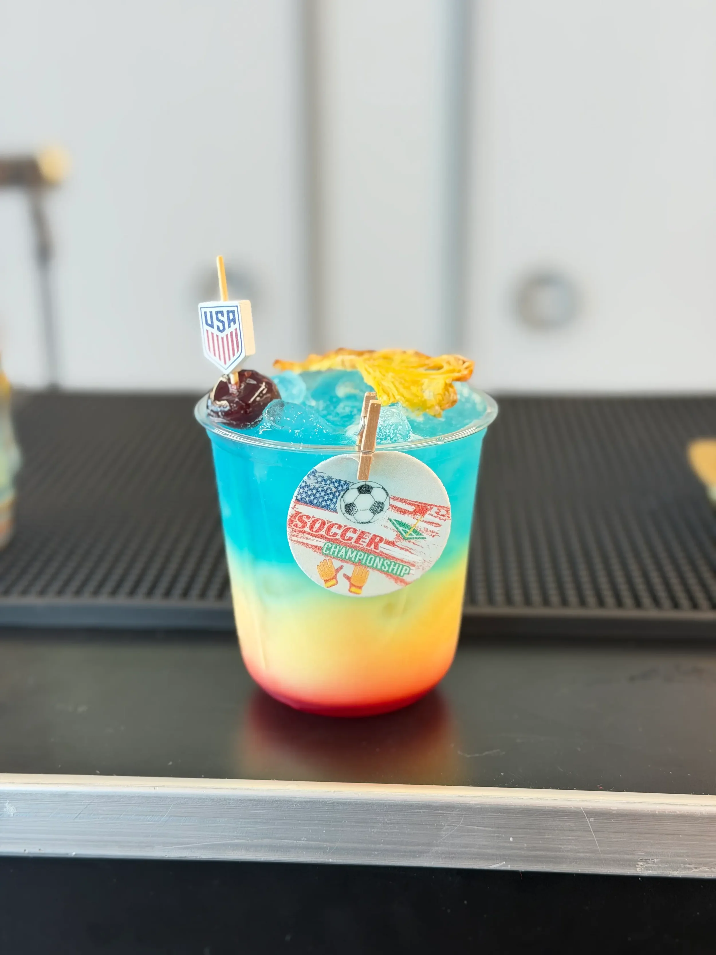 Custom signature cocktail created for FanDuel's FIFA corporate watch party in Orlando, featuring red, yellow, and blue colors, handcrafted garnishes, and premium presentation for an engaging employee happy hour.