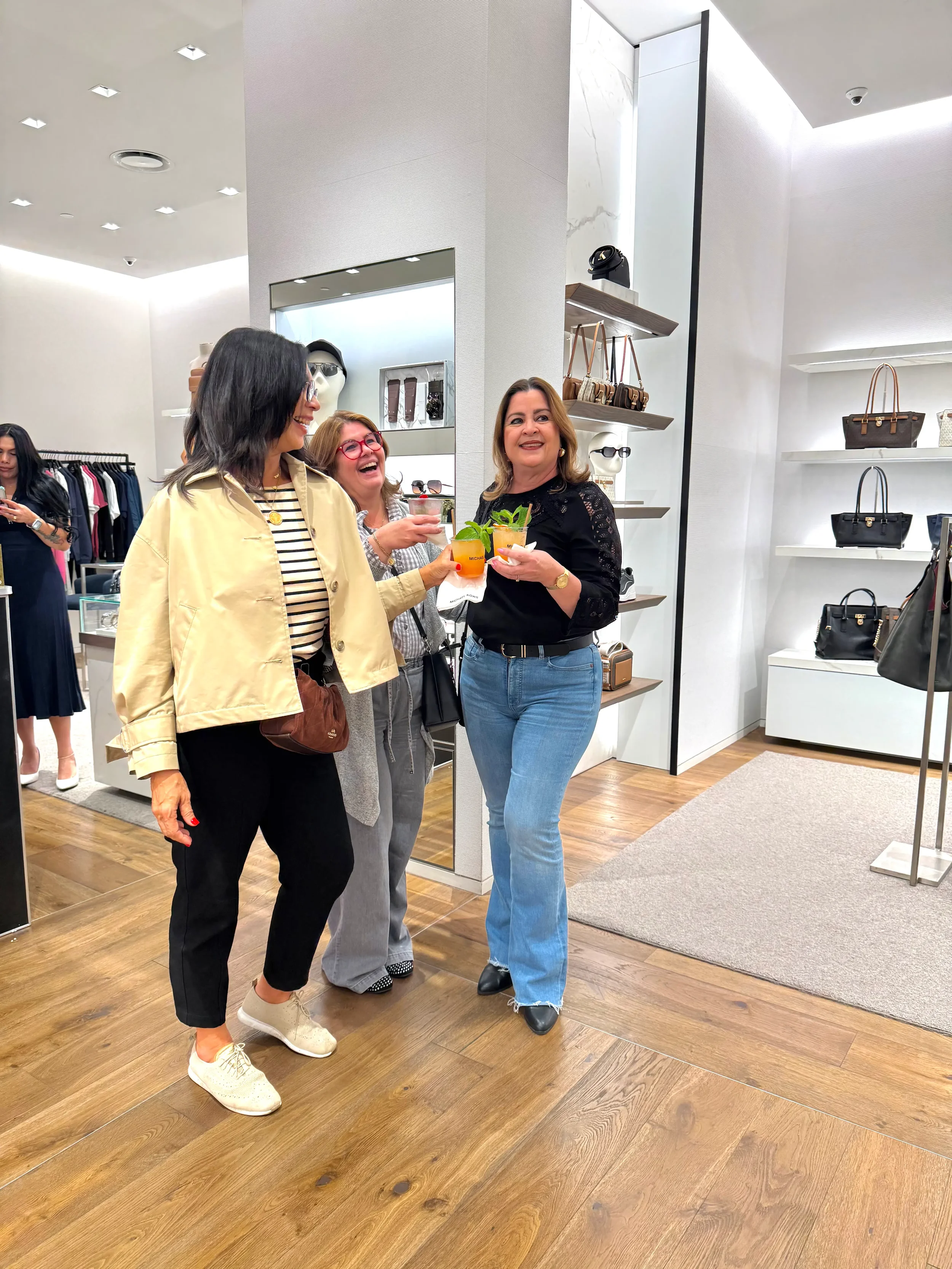Clients smiling while holding custom mocktails during a Michael Kors retail brand activation in Miami, featuring branded cups and premium mobile bar service by Pisco Mixers.