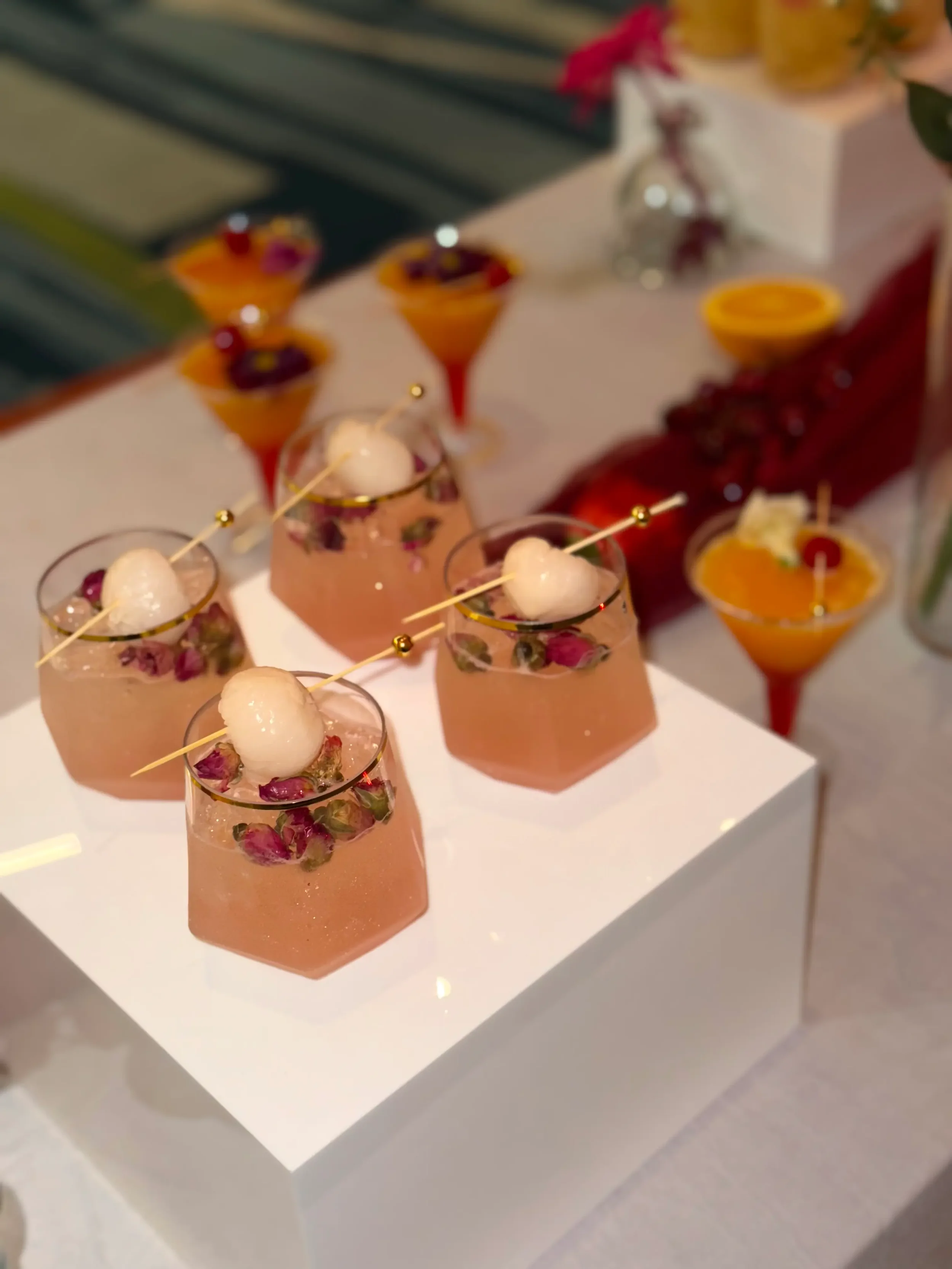 Signature piña colada and lychee mocktails beautifully displayed on decorative risers as a luxury mobile bar enhancement for weddings, corporate events, and private parties by Pisco Mixers.