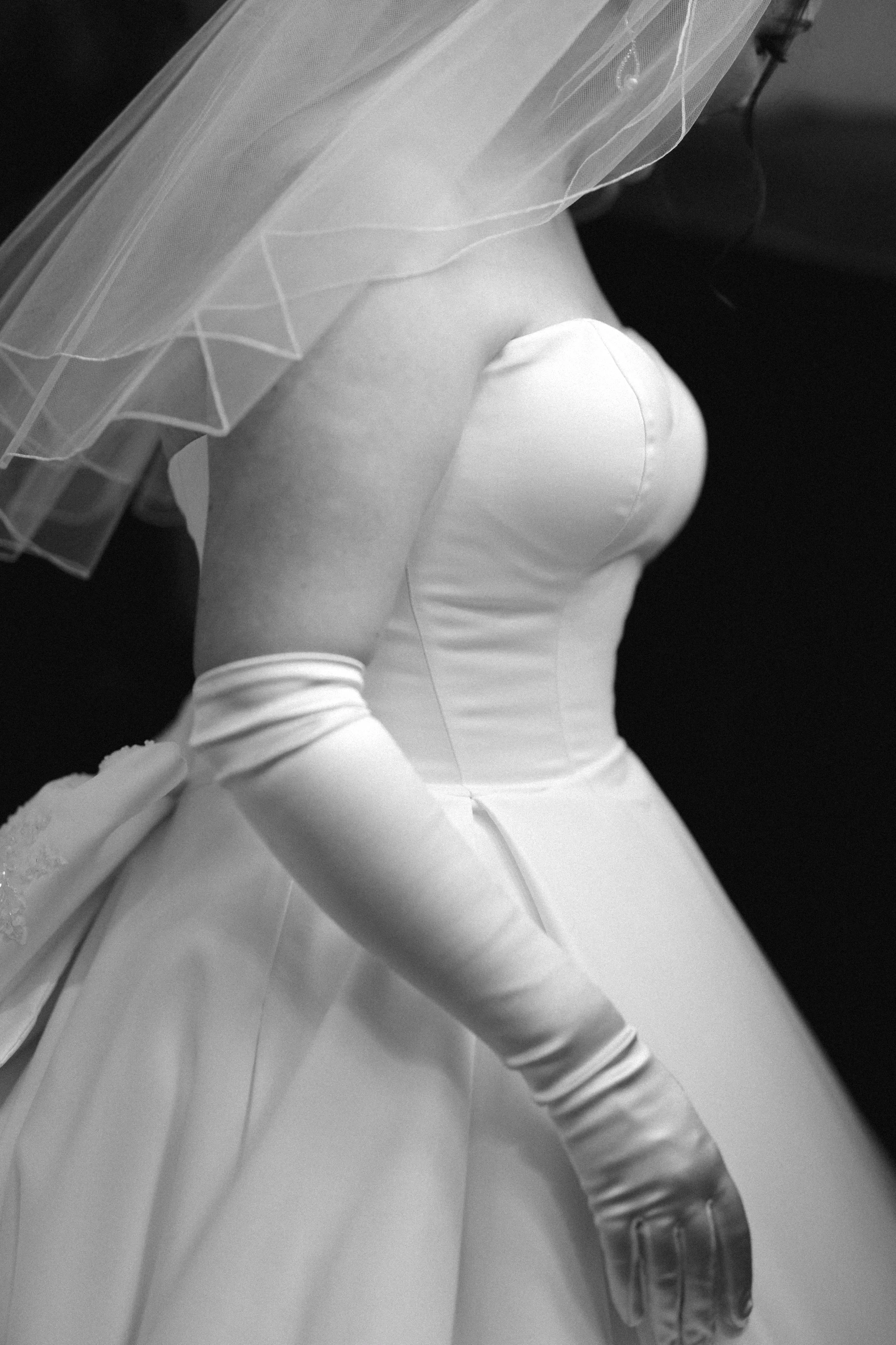 Close-up of a bride's torso wearing a wedding dress with long gloves and a veil.