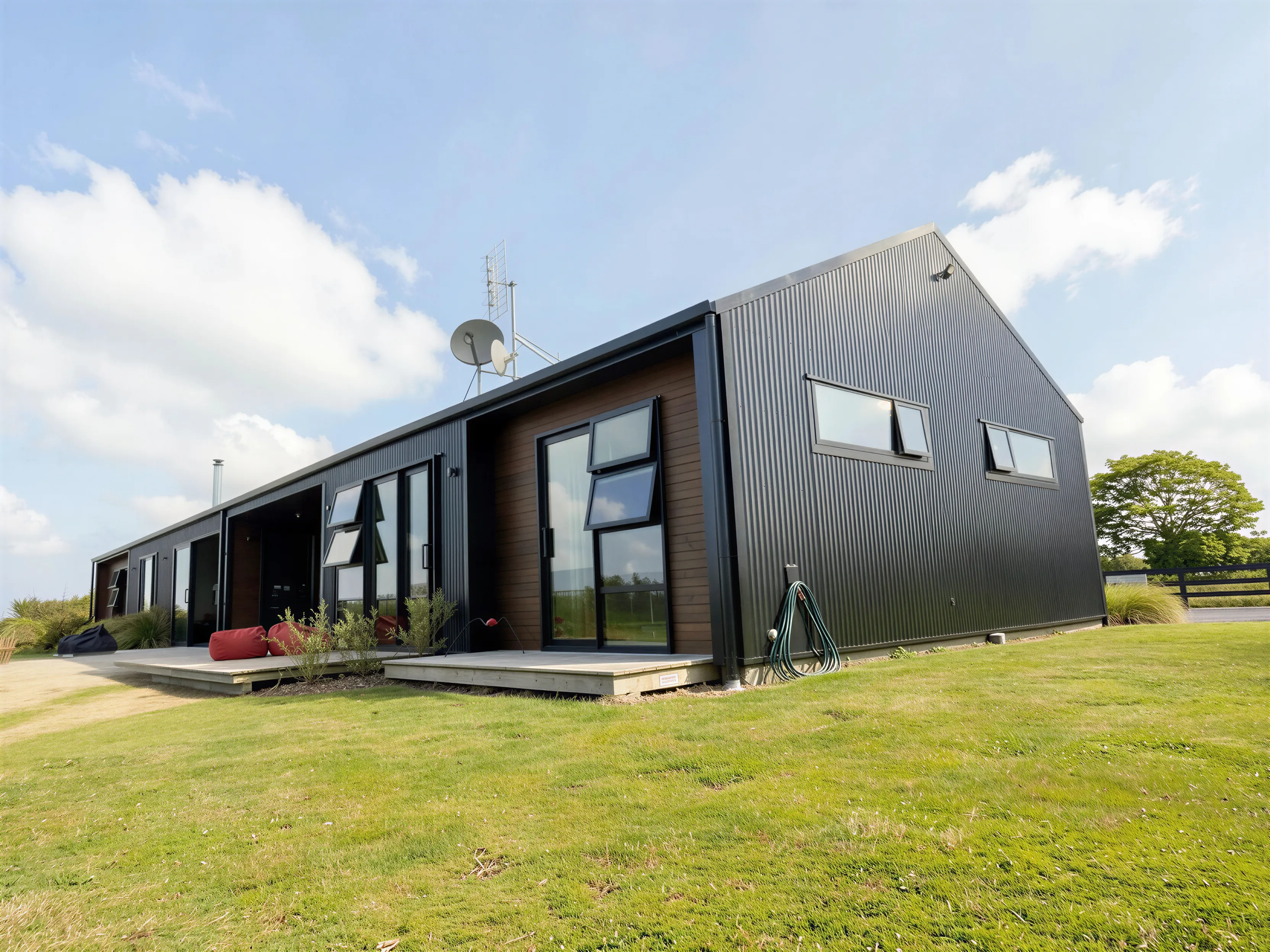 Exterior, long low home with metal cladding set in paddock grass
