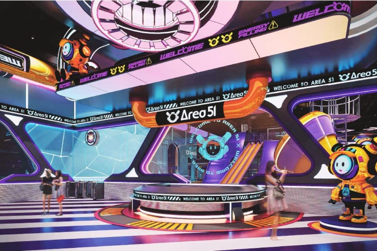 A futuristic arcade entrance with neon lights and sci-fi themed decorations, including robots and digital displays, welcoming visitors to Area 51.