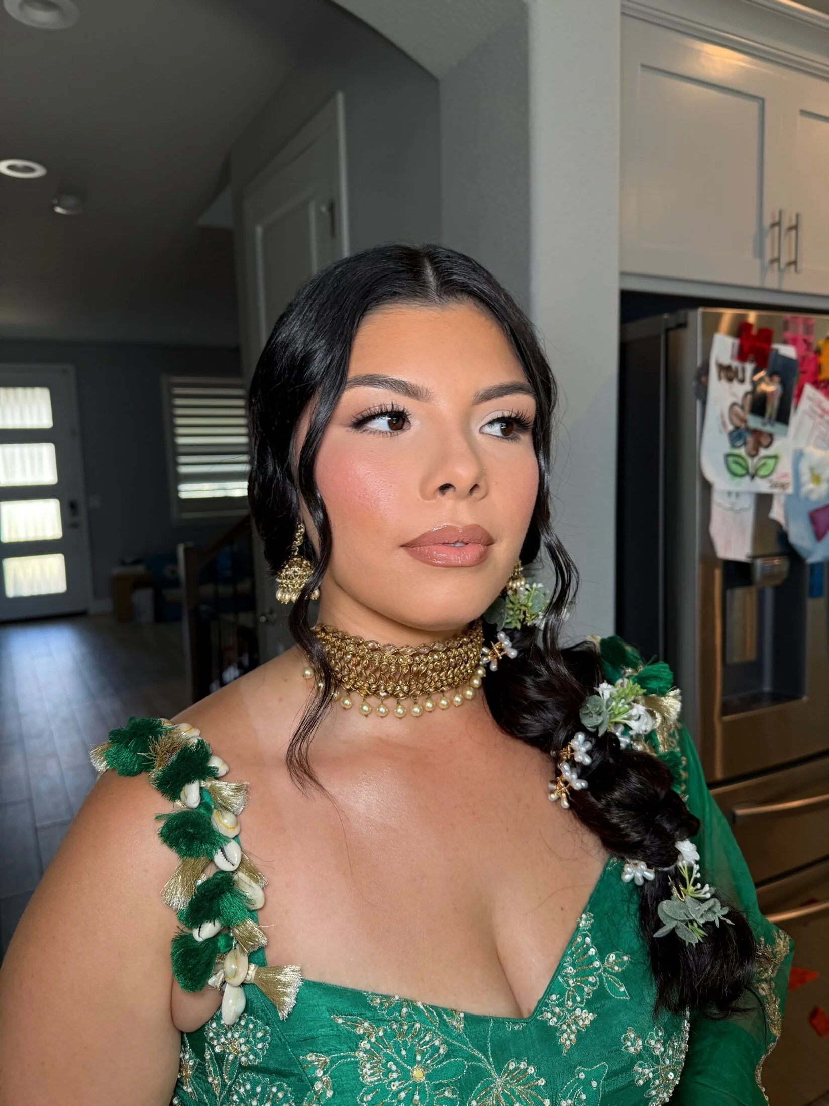 Fresh, luminous makeup by Glam by Manpreet with a soft braid and green floral details.