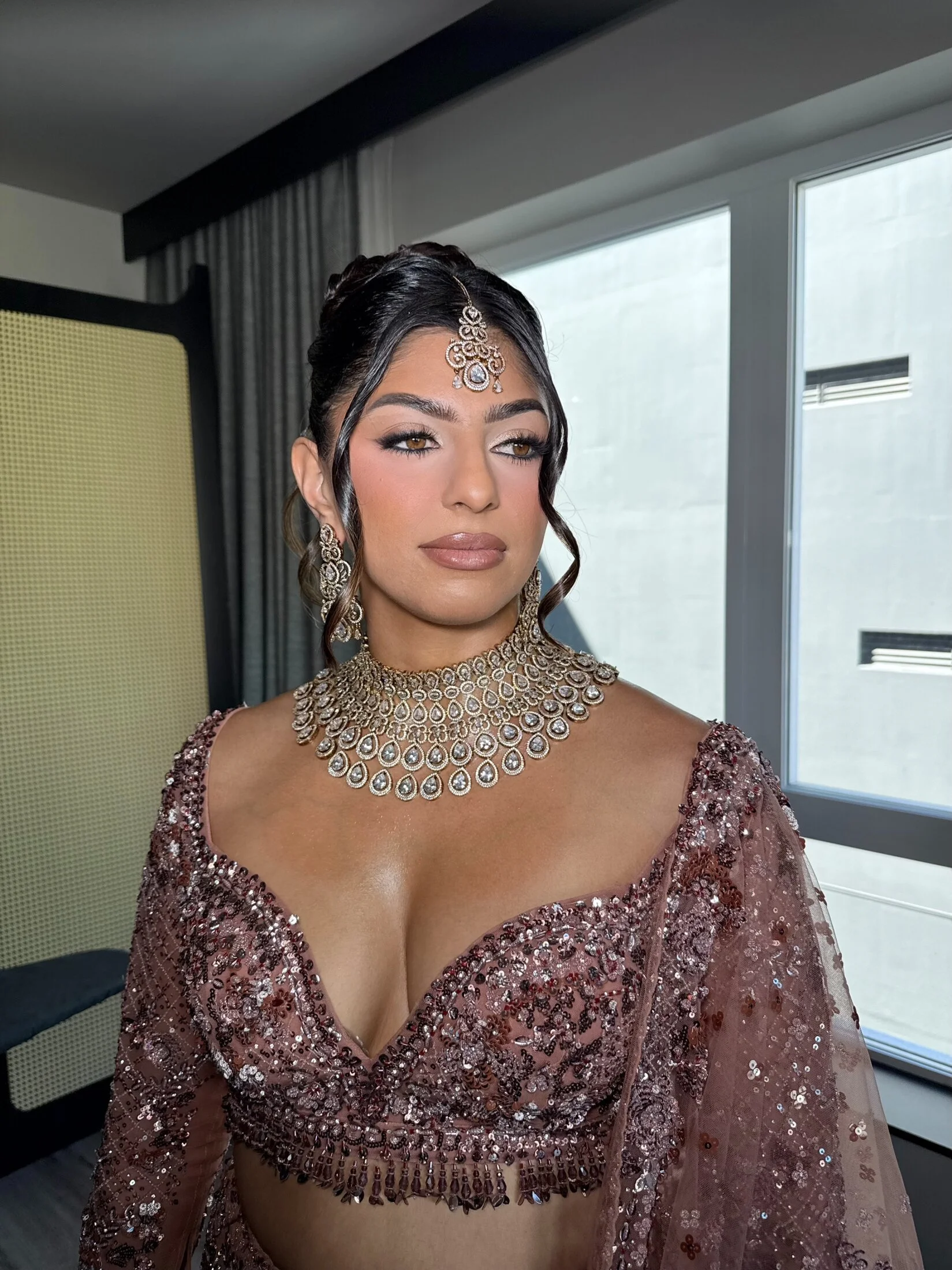 Modern South Asian glamour with softly sculpted makeup and an elegant updo.