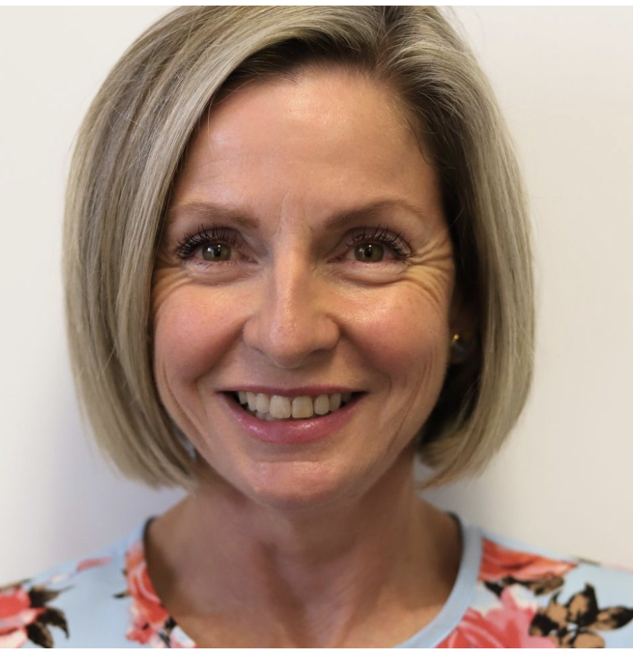 A woman with short blonde hair, smiling, wearing a floral top.