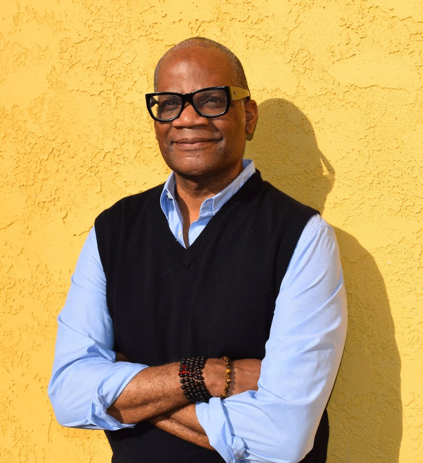 Darryl leaning against a yellow wall