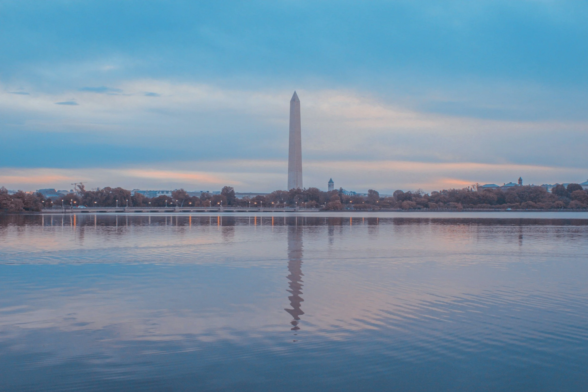 Washington Monument reflected in the water during sunset with a partly cloudy sky