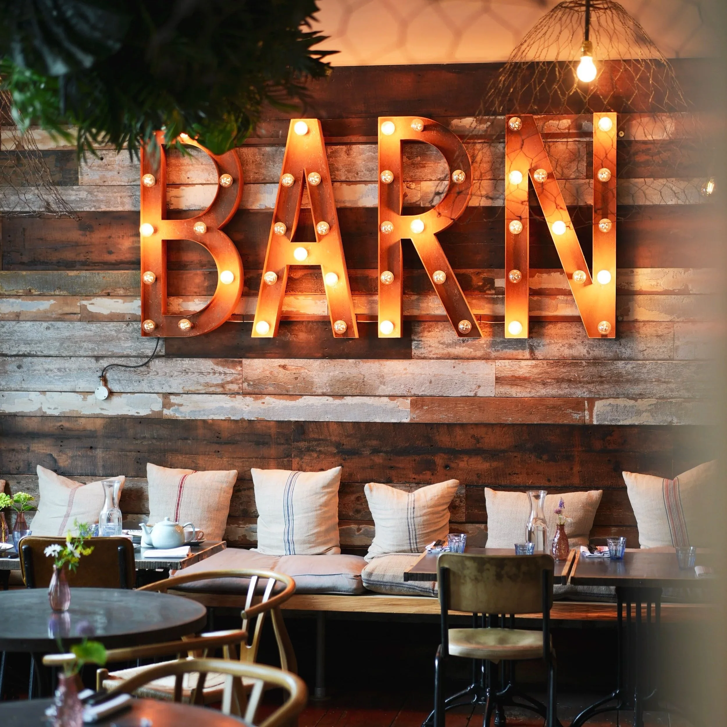 Artist Residence Penzance, tucked into The Cornish Barn - rustic textures, glowing lights and a cosy corner made for long lunches, relaxed dinners and seaside suppers.