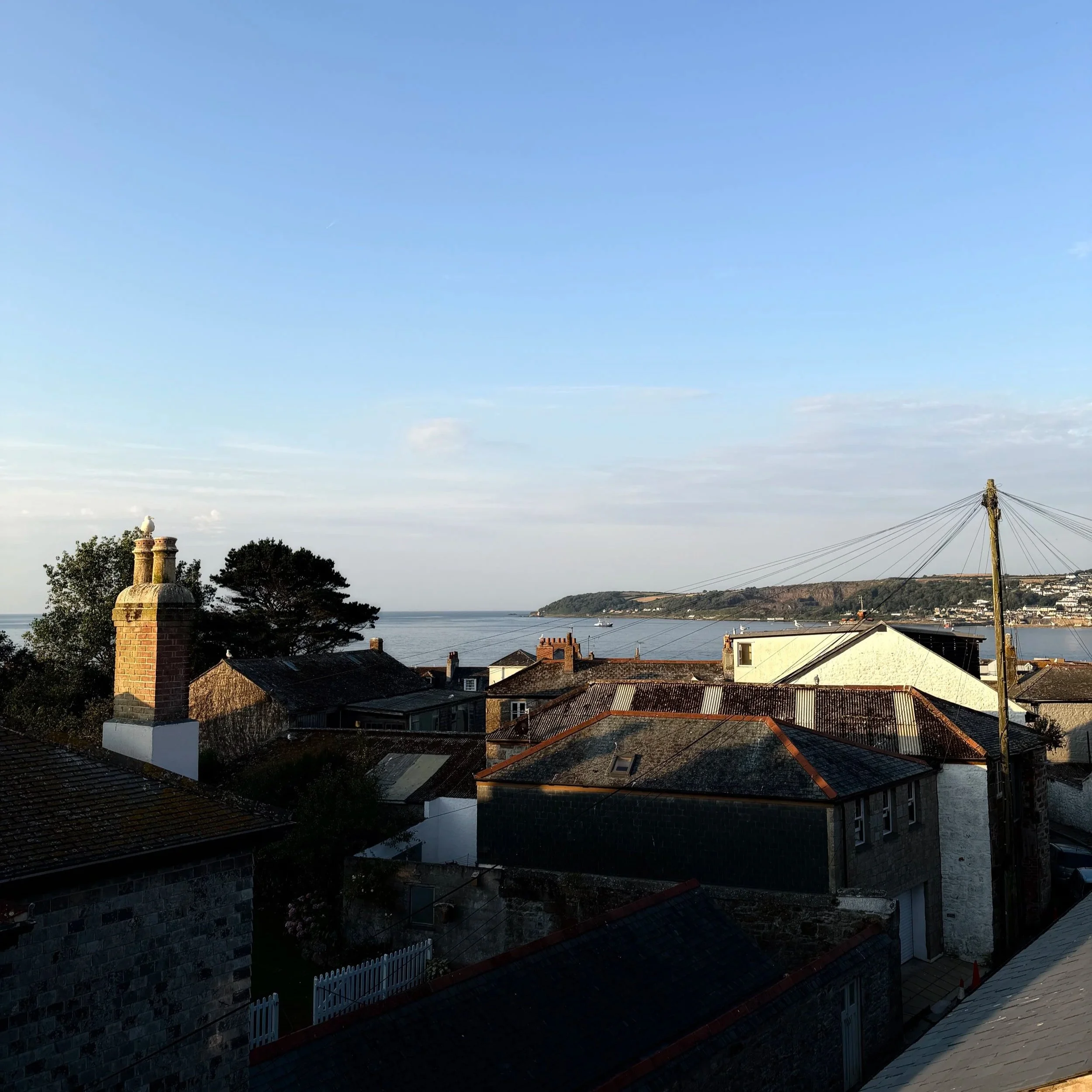 Artist Residence Penzance views - rooftops, sea air and golden Cornish light, with the coast just beyond the chimney tops.