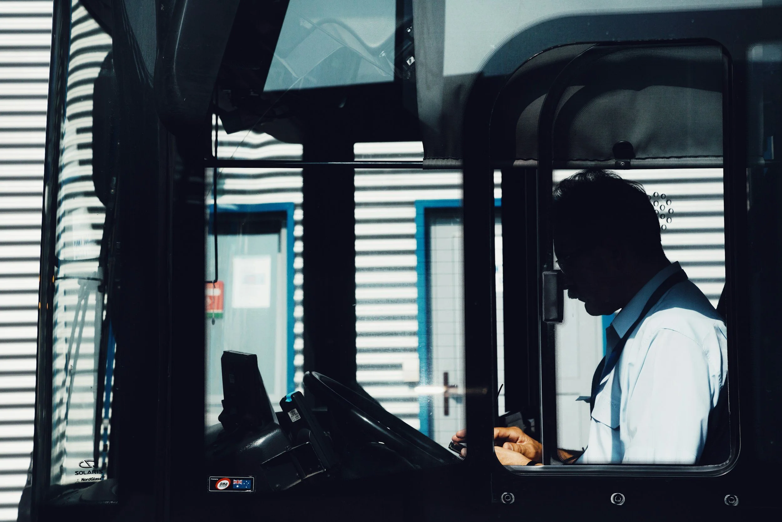 A person in a white uniform with a dark tie operating an electronic ticketing or check-in kiosk.