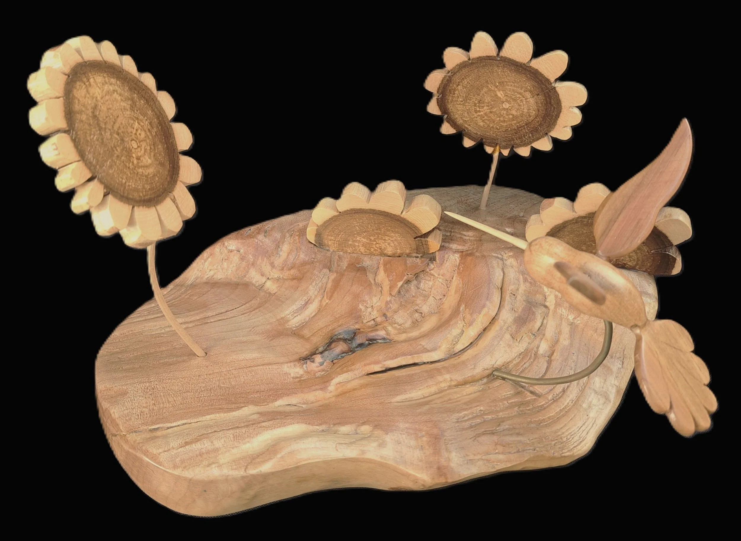Wooden sculpture of sunflower flowers on a curved wooden base with a black background.